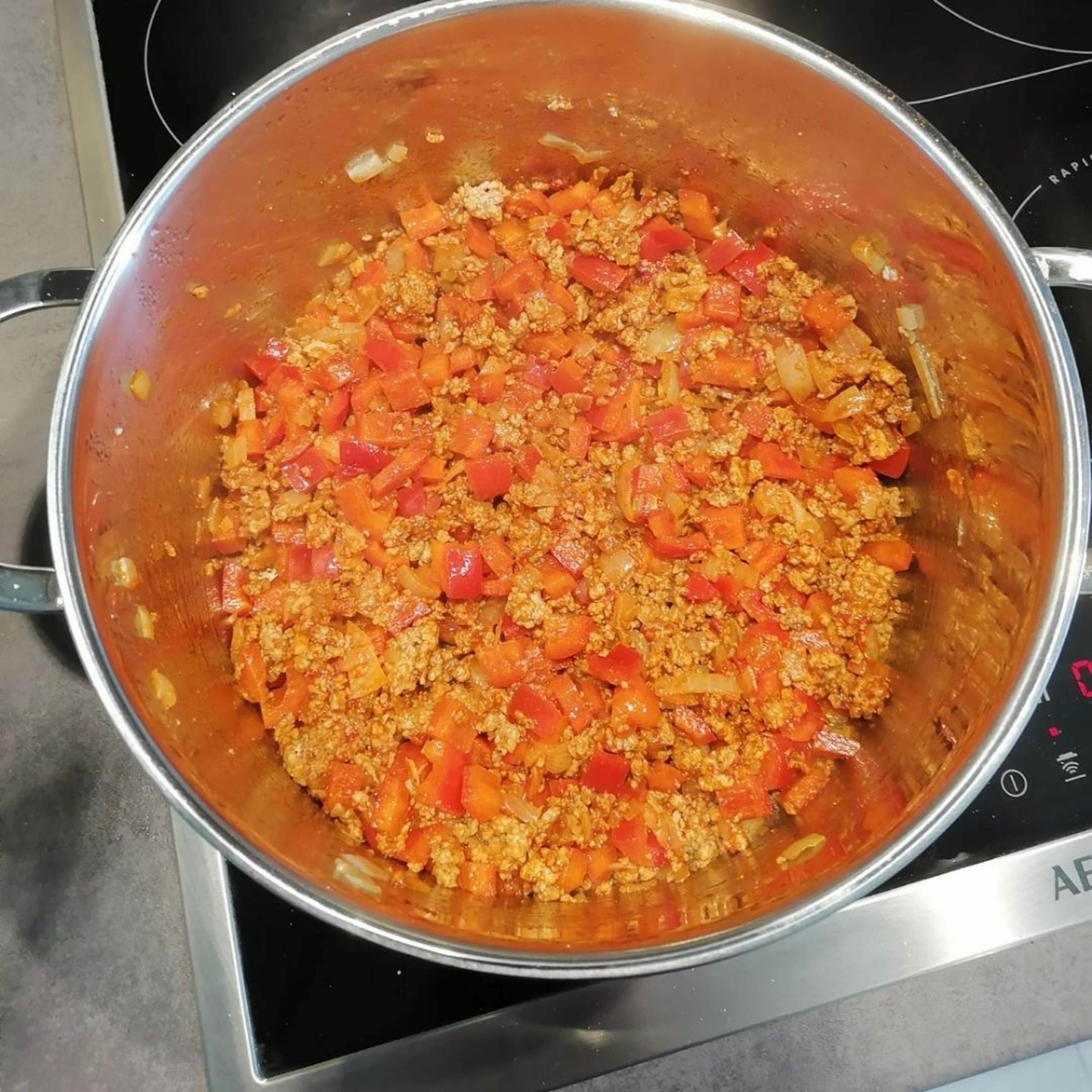 Nach dem die Gewürze und das Tomatenmark untergerührt wurden, die geschnittene Paprika hinzufügen und alles für 5 Minuten köcheln lassen.