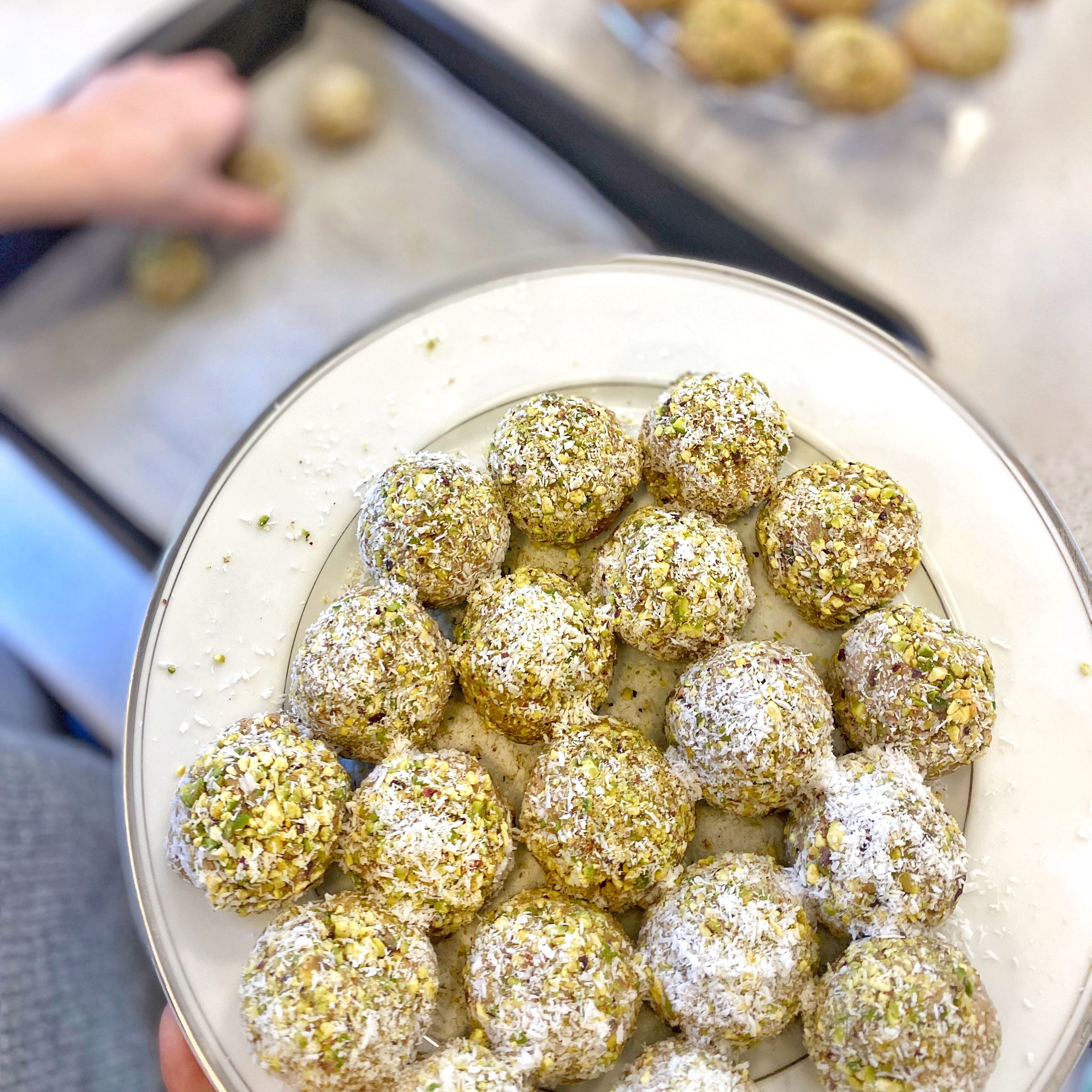 Roll cookie dough balls into shredded coconut and ground pistachios (optional).