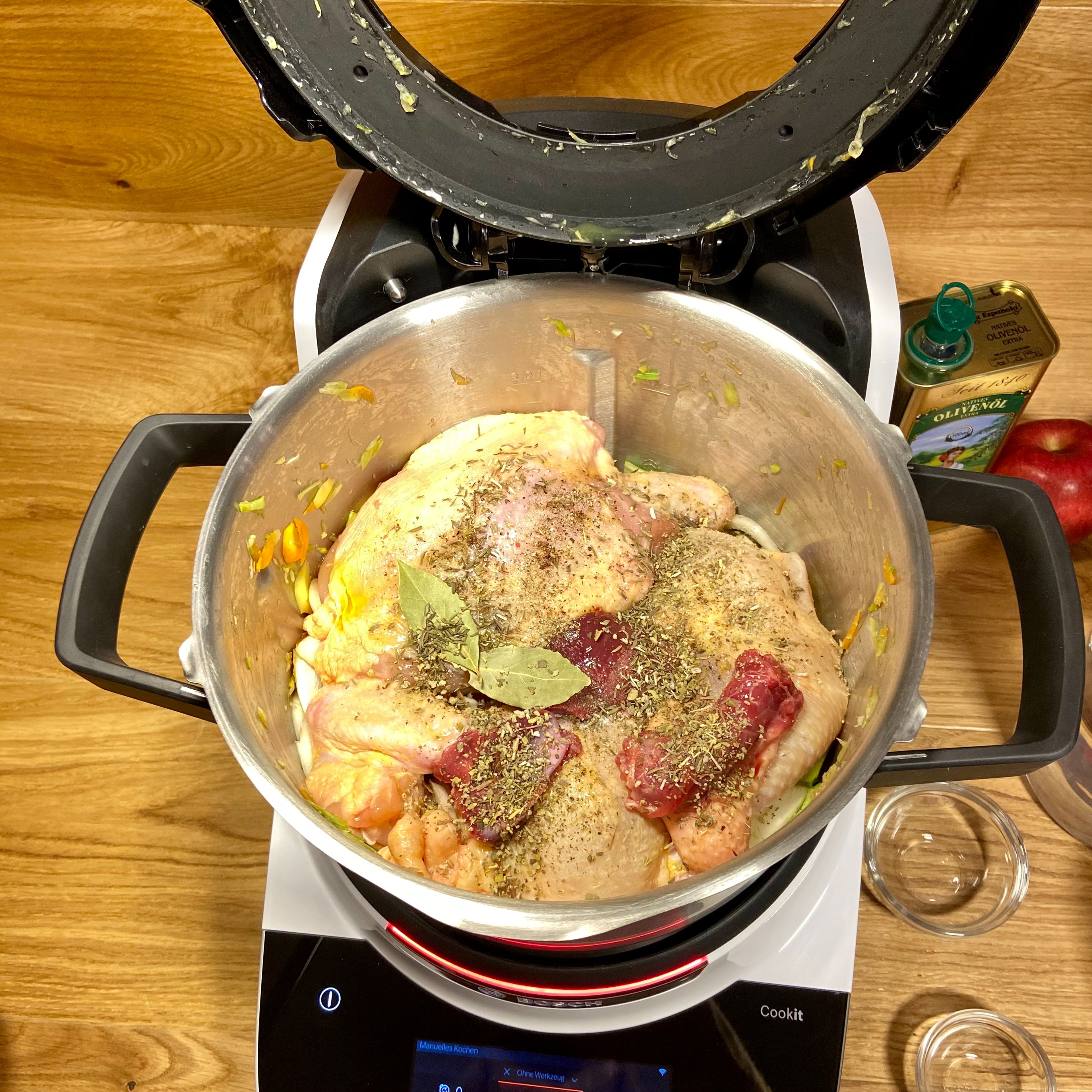 Das Suppenhuhn mit den Innereien, dem Salbei, Salz, Pfeffer, Öl und den Lorbeerblättern in den Cookit auf das Gemüse geben.