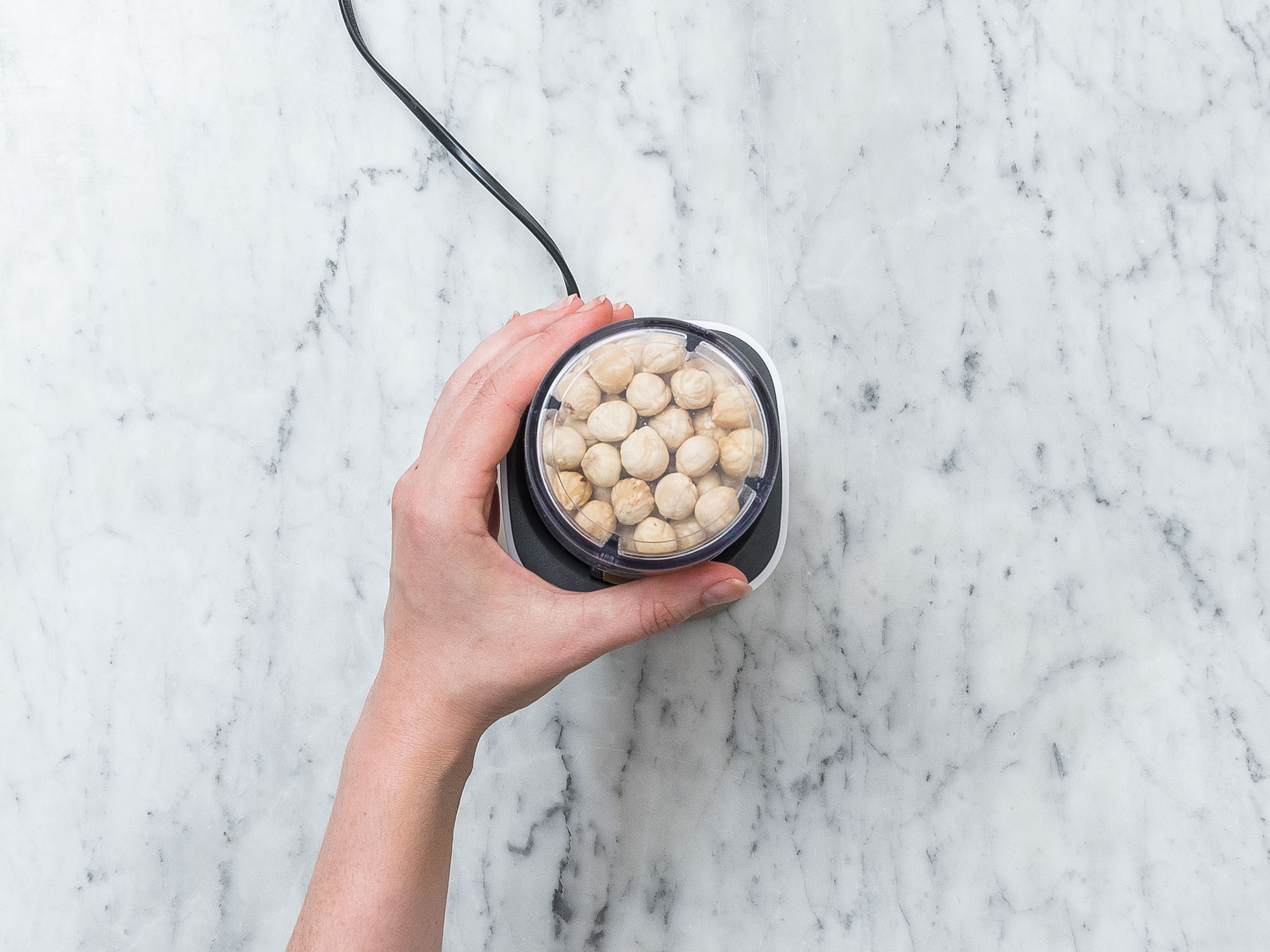 Toast hazelnuts in a frying pan set over medium heat for approx. 5 min. Transfer hot hazelnuts to a kitchen towel. Rub together to peel nuts. Transfer skinned hazelnuts to a food processor and blend for approx. 10 min., or until creamy.