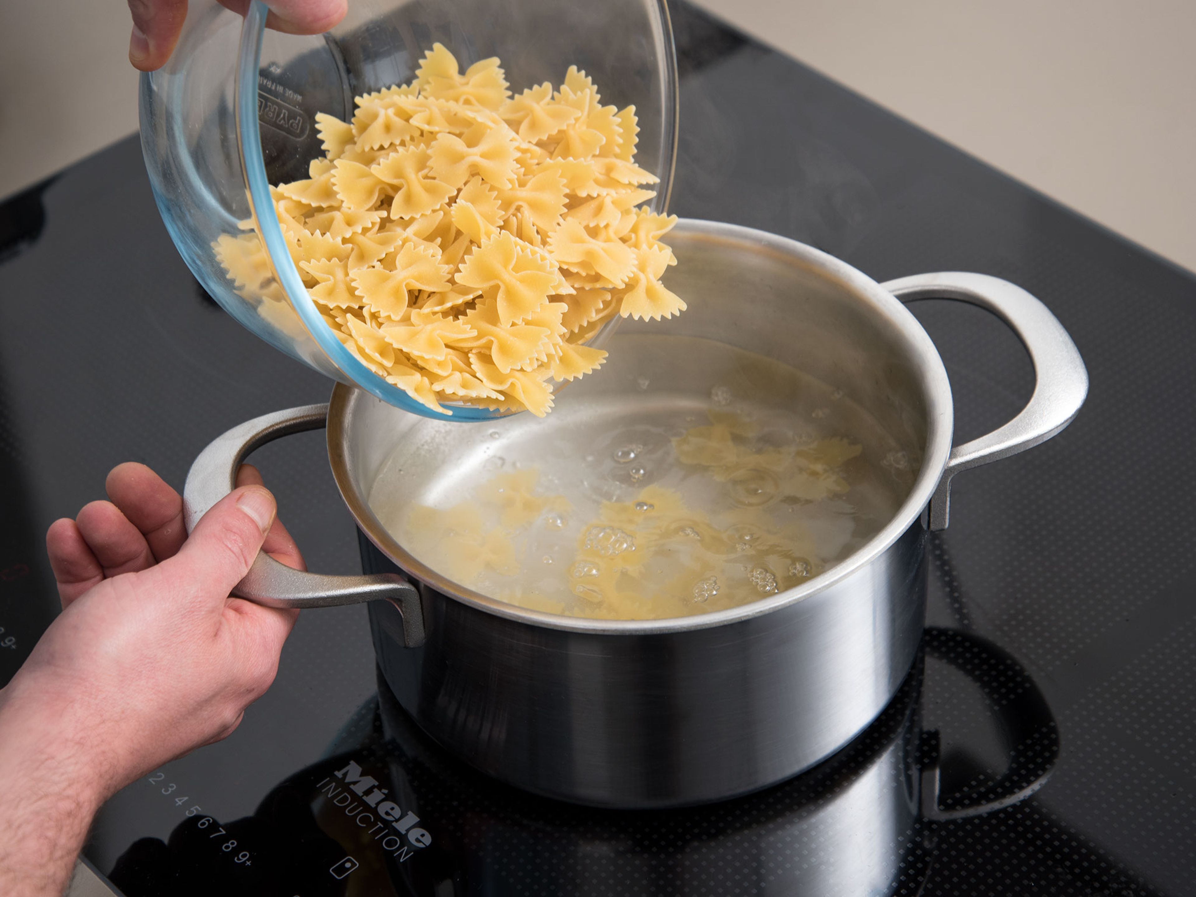 In another pot of boiling, salted water, cook the farfalle until al dente and strain into colander and drain.