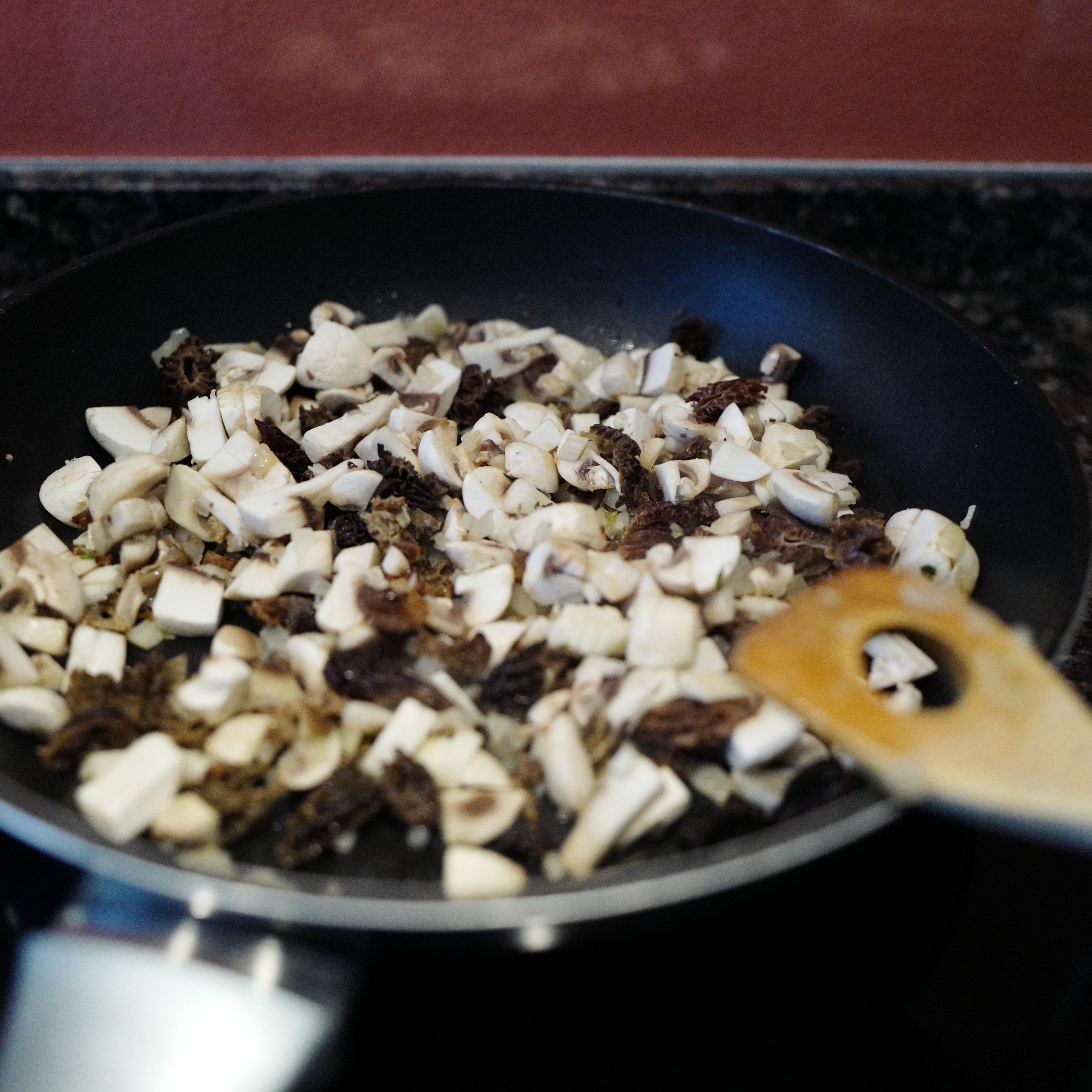 Ein wenig Öl in eine beschichtete Pfanne geben und die Zwiebel darin glasig dünsten. Die gehackten Pilze und den Knoblauch dazu geben und ca. 5-6 min braten.