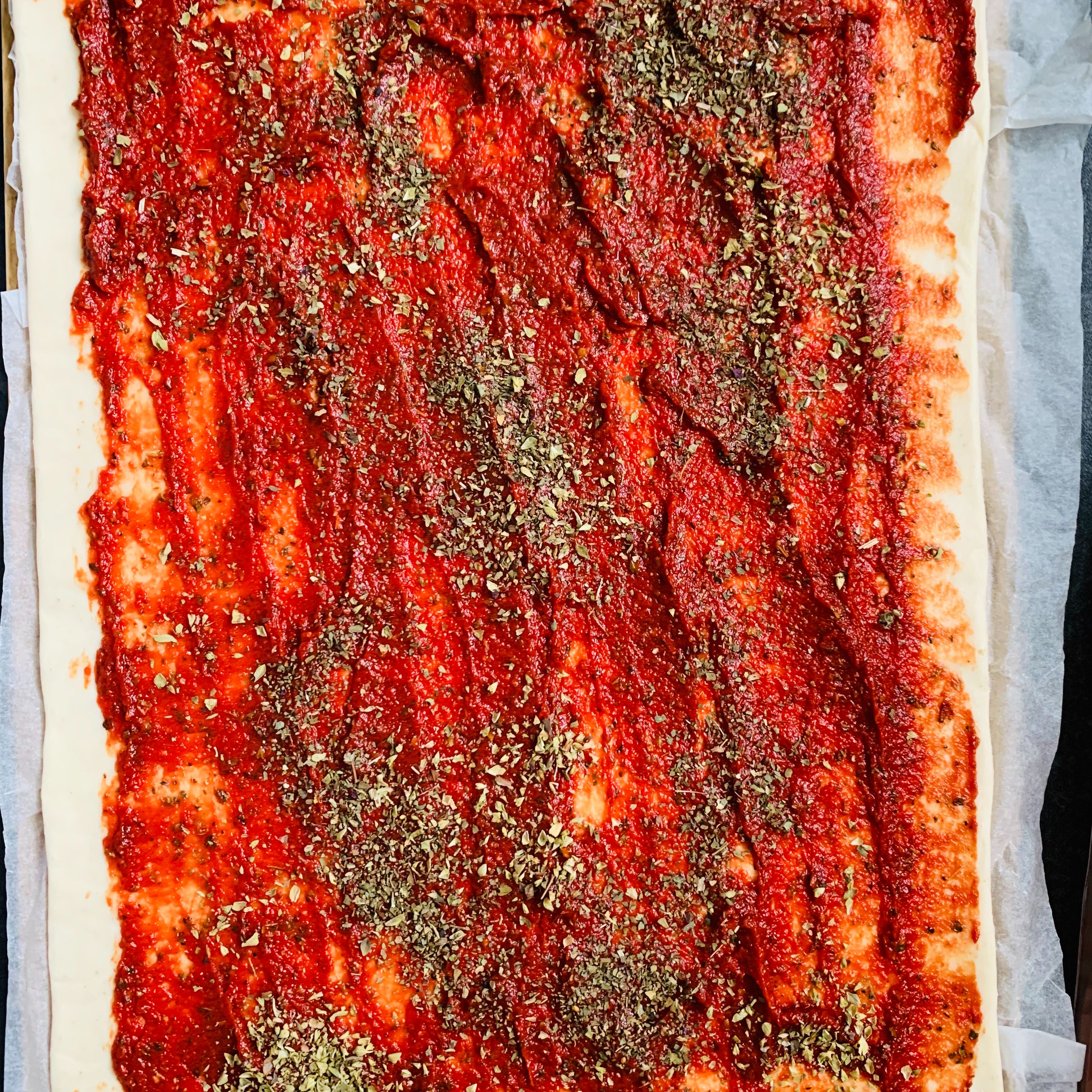 Open up the pizza dough and spread the tomato purée mix all over it. Sprinkle some more herbs over it. 
