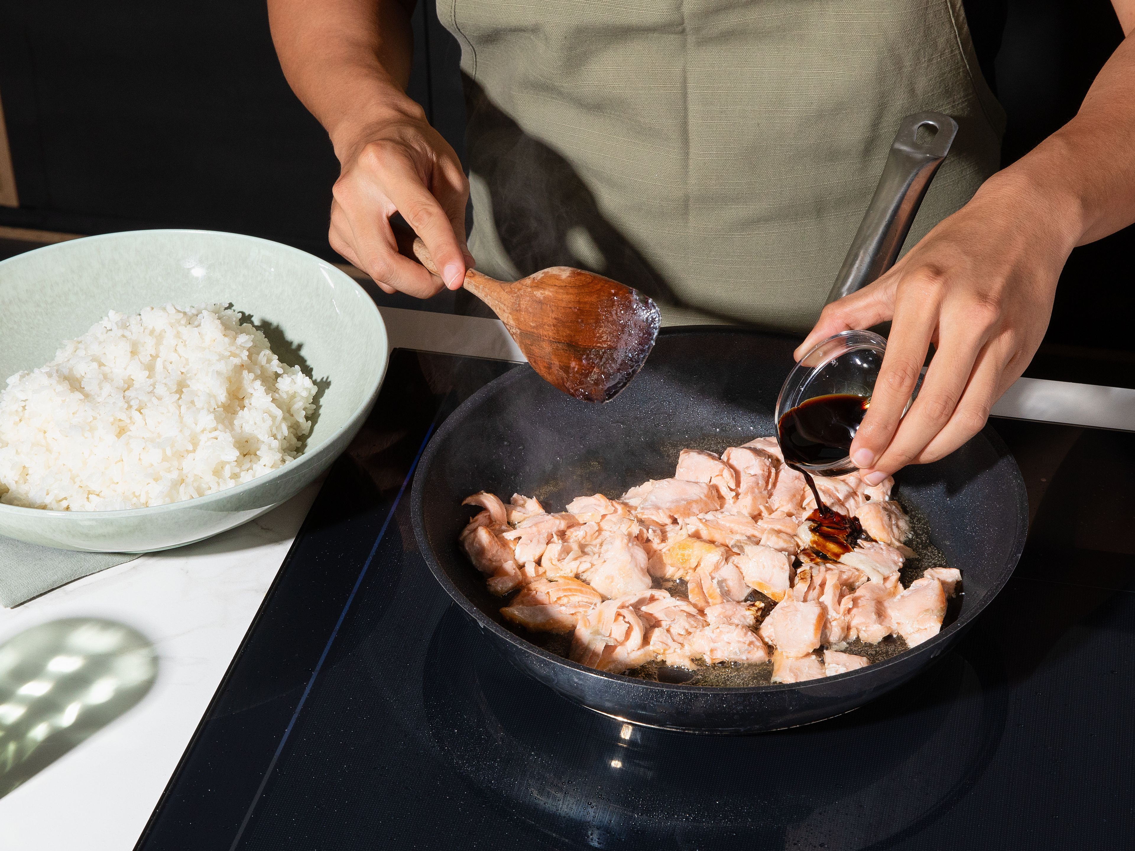 Den Sushireis nach Packungsanweisung kochen. Reisessig und Zucker unter den noch warmen Reis mischen, damit er besser klebt, dann leicht abkühlen lassen. Währenddessen den Lachs in einer Pfanne ca. 5–7 Min. rundherum anbraten, bis er gar ist. Den Fisch in kleine Stücke zerteilen, mit Sojasoße ablöschen und kurz durchschwenken. Die Frühlingszwiebeln in feine Ringe schneiden.