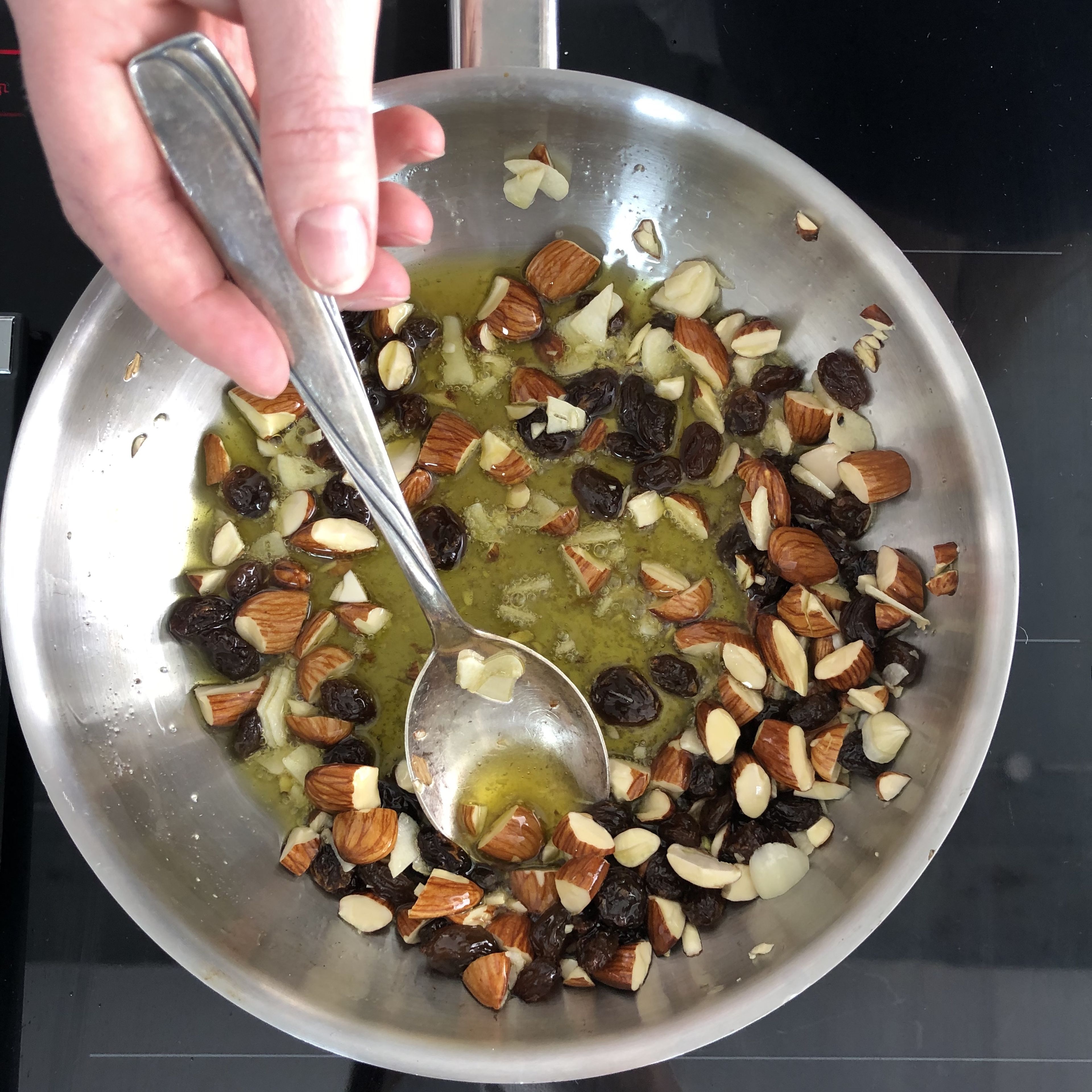 For the crunchy topping, heat olive oil in a pan, add almonds and fry briefly. Then add garlic and raisins and fry until everything is crispy and brown. Transfer to a bowl and set aside.