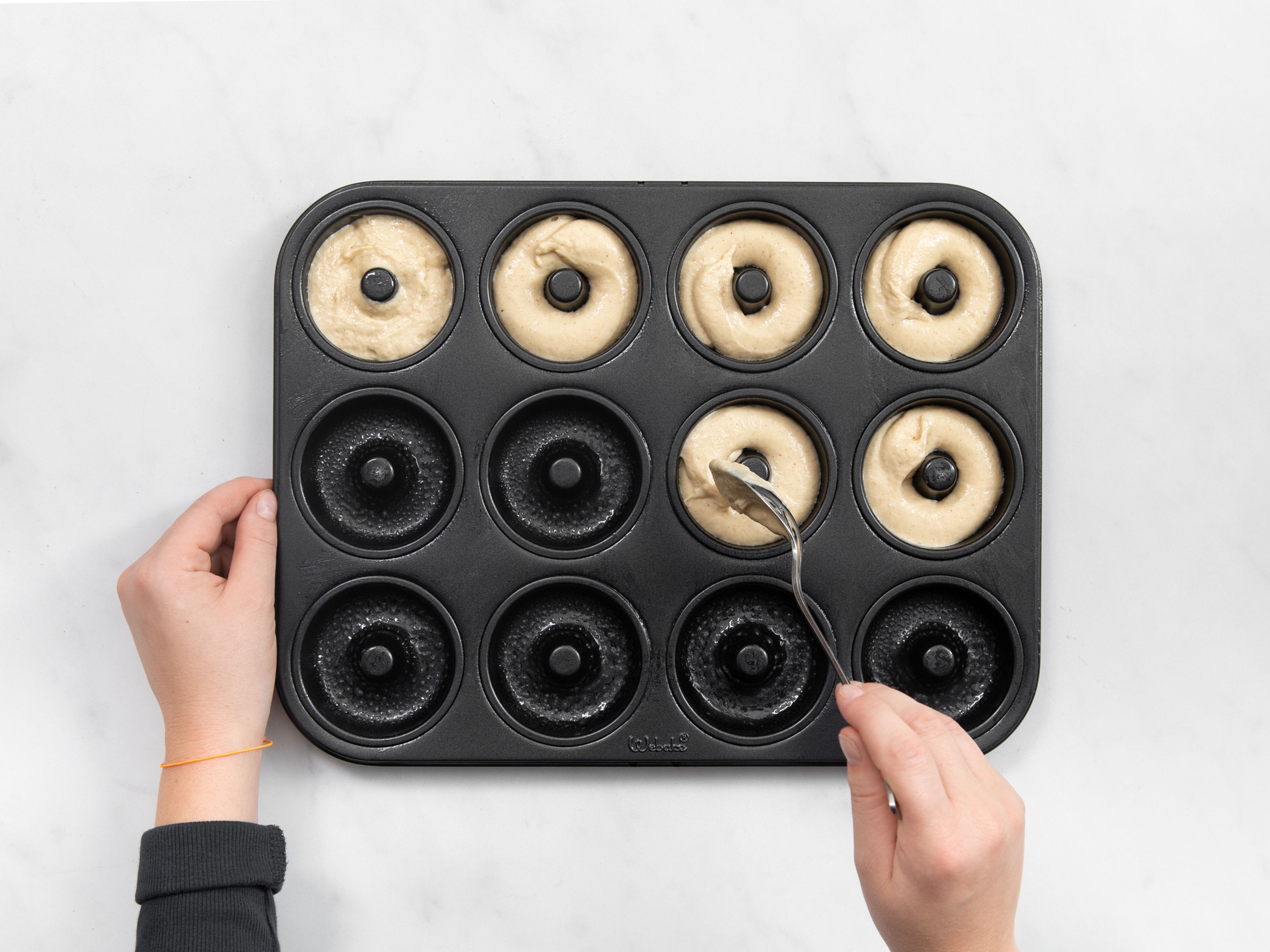 Use a spoon to drop spoonfuls of batter into a greased doughnut pan. Smooth the tops, leaving about 1/4-inch at the top of each well. Bake for about 10 min., then let cool for at least 5 min. before inverting the pan and gently tapping out the doughnuts onto a cooling rack.