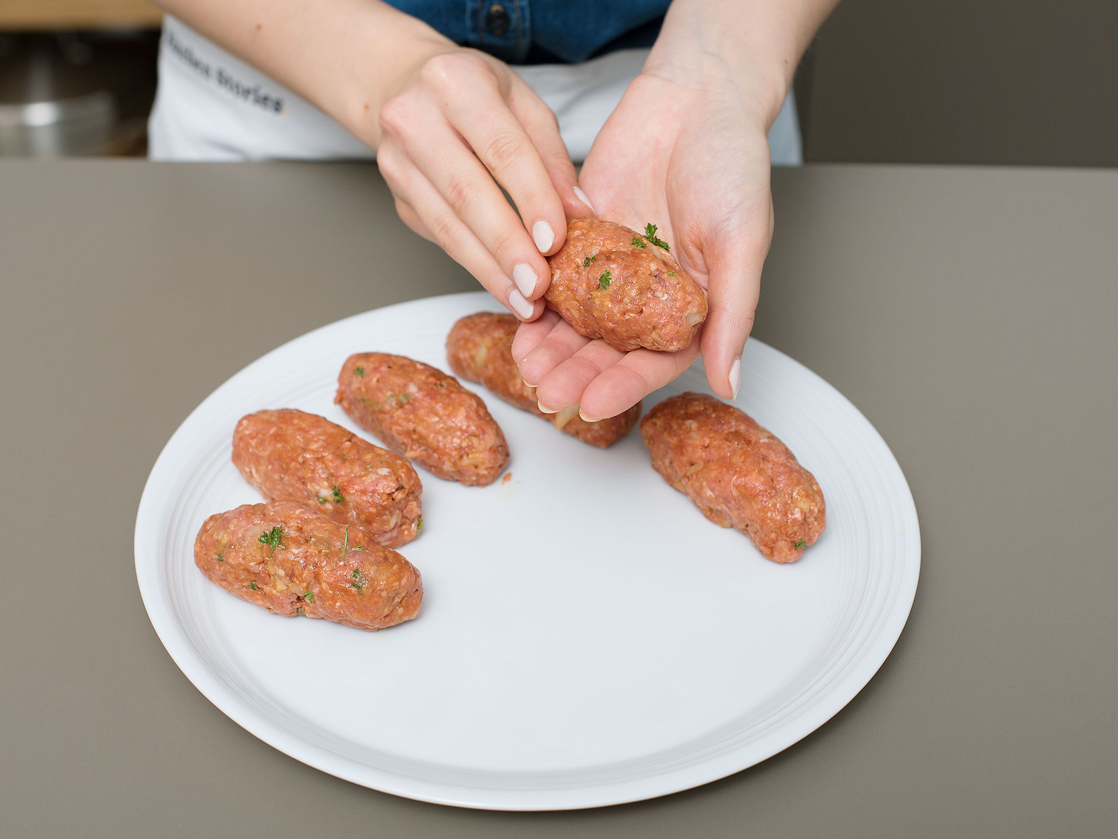Die Hackfleischmischung mit angefeuchteten Händen zu gleichgroßen Röllchen formen. Auf einen Teller legen und ca. 1 Stunde im Kühlschrank ruhen lassen.