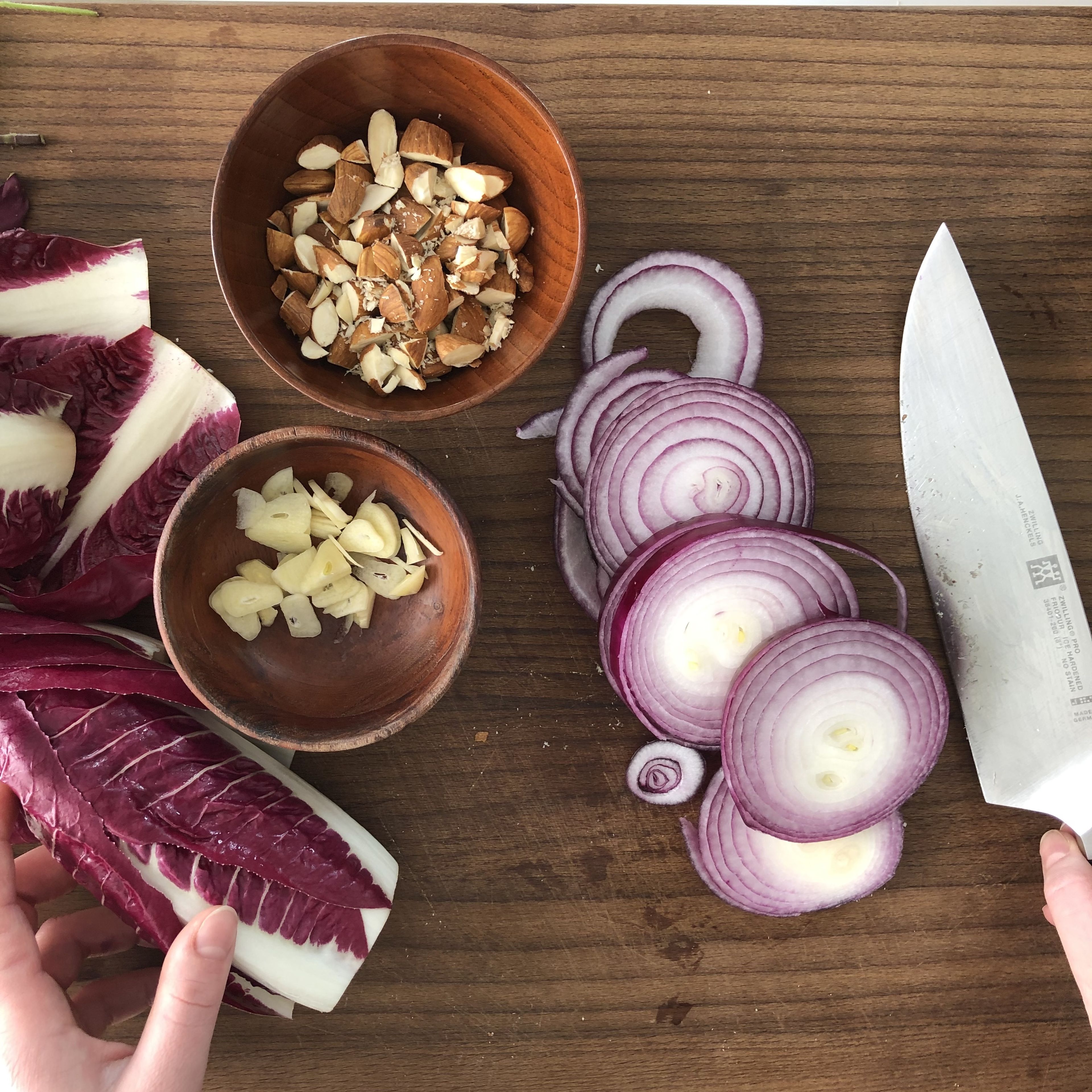 Peel the onion and garlic. Cut the onion in rings and the garlic in fine slices. Coarsely chop the almonds. Remove the stalk from the radicchio and separate the leaves.