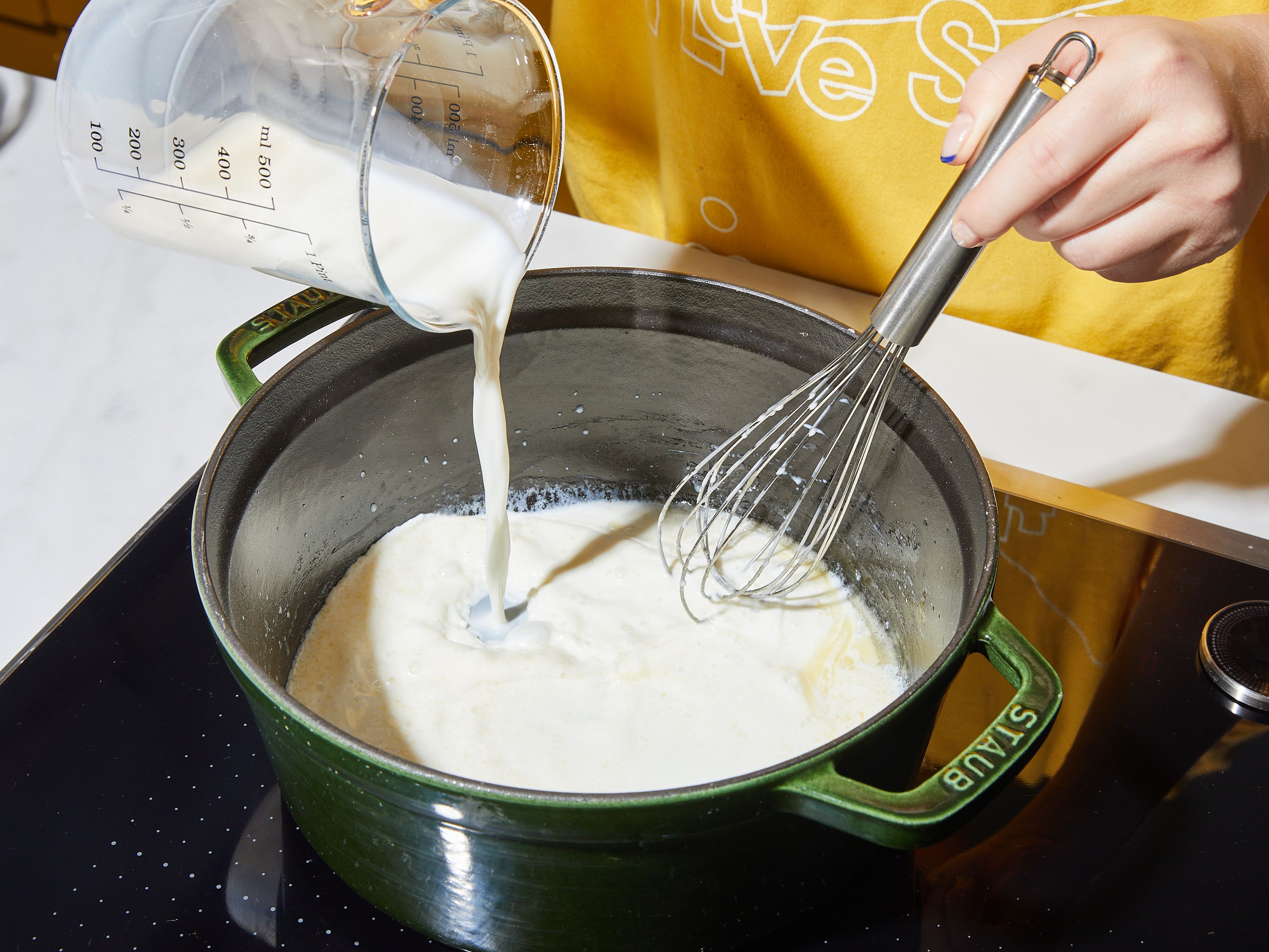 Cheddar-Käse mit einer Küchenmaschine oder einer Küchenreibe zerkleinern und beiseite stellen. Butter in einem großen Topf bei mittlerer Hitze schmelzen. Mehl einrühren und kochen lassen, bis die Mischung eingedickt ist und eine leicht goldene Farbe annimmt, ca. 2 Min. Dann einen Teil der Milch einrühren. Sobald die Masse eingedickt ist, die restliche Milch und das Wasser hinzufügen und zum Köcheln bringen.