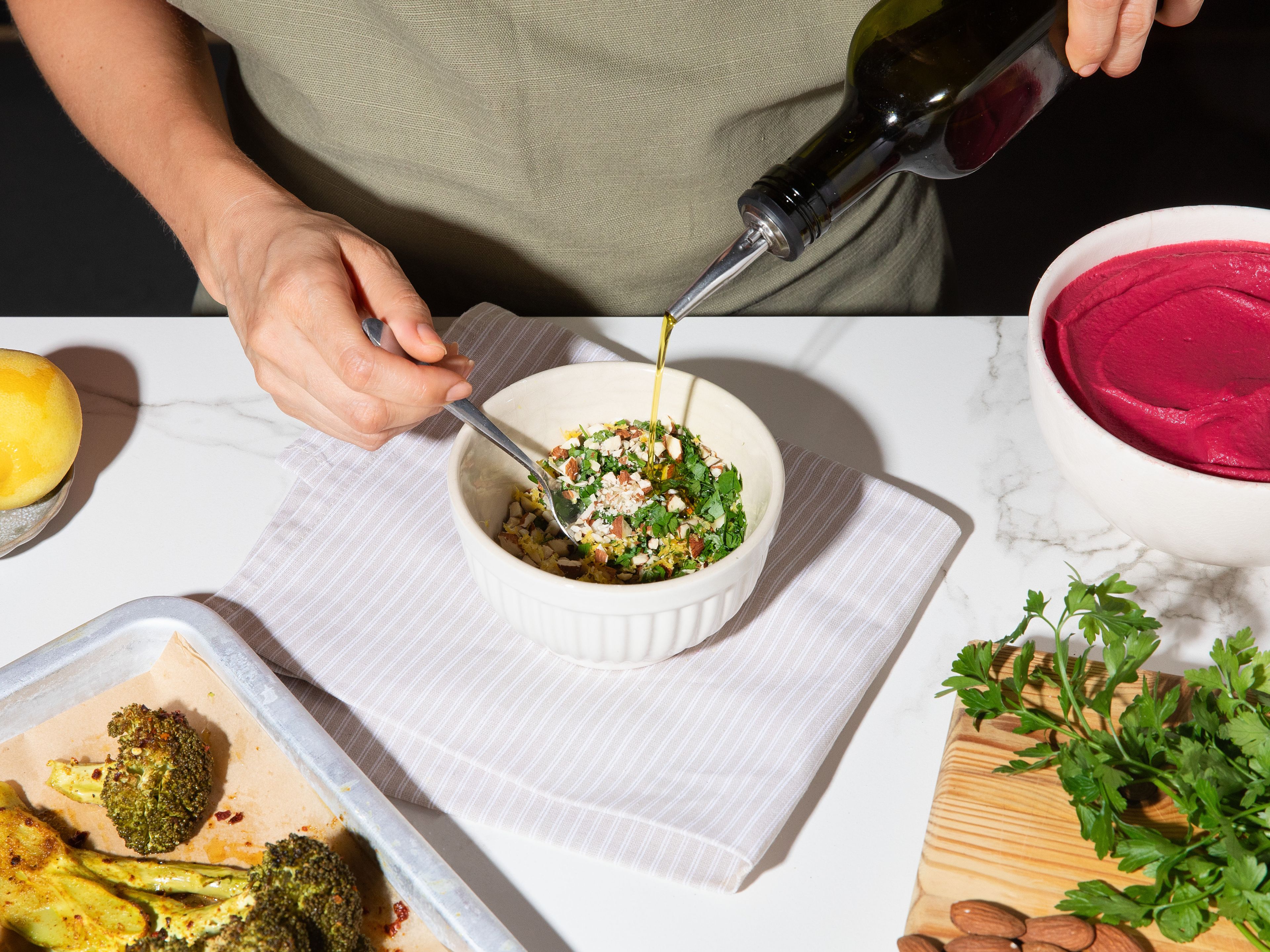 For almond gremolata, coarsely chop almonds. Finely chop parsley and finely grate remaining garlic. Zest lemon and mix in small bowl with almonds, parsley, salt, and pepper. Spread beetroot hummus on plates and arrange roasted broccoli steaks on top. Top with crumbled feta and almond gremolata, add little more olive oil if desired, and serve immediately.
