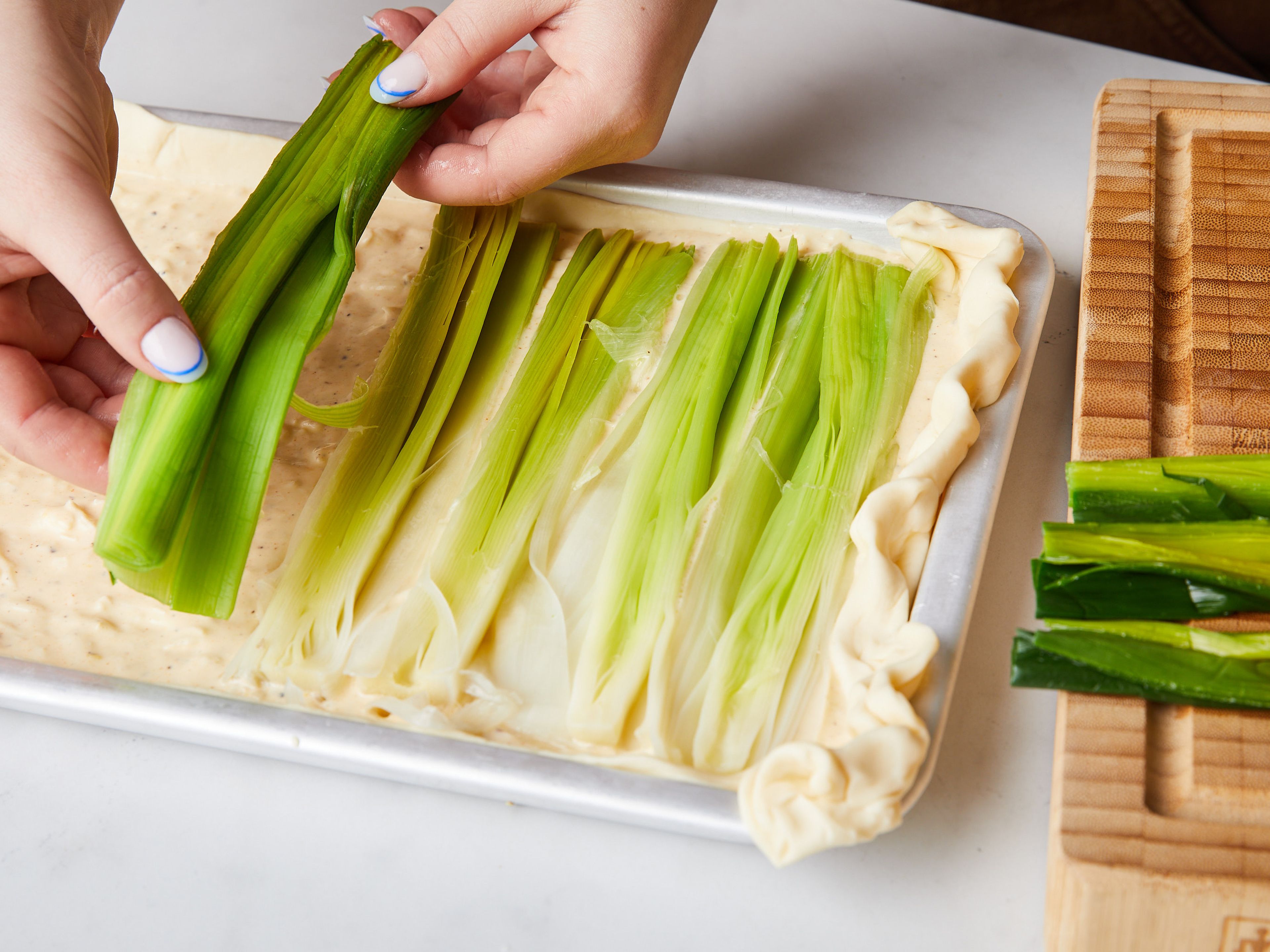 Place the puff pastry into the baking sheet so the entire bottom is covered and you get a small crust around the edges. Pour in the crème fraîche mixture and spread evenly over the base. Then press the halved leeks into the mixture with the cut-side facing up. Bake for approx. 30 min. at 200°C/400°F until golden-brown. Slice and enjoy warm or room temperature!