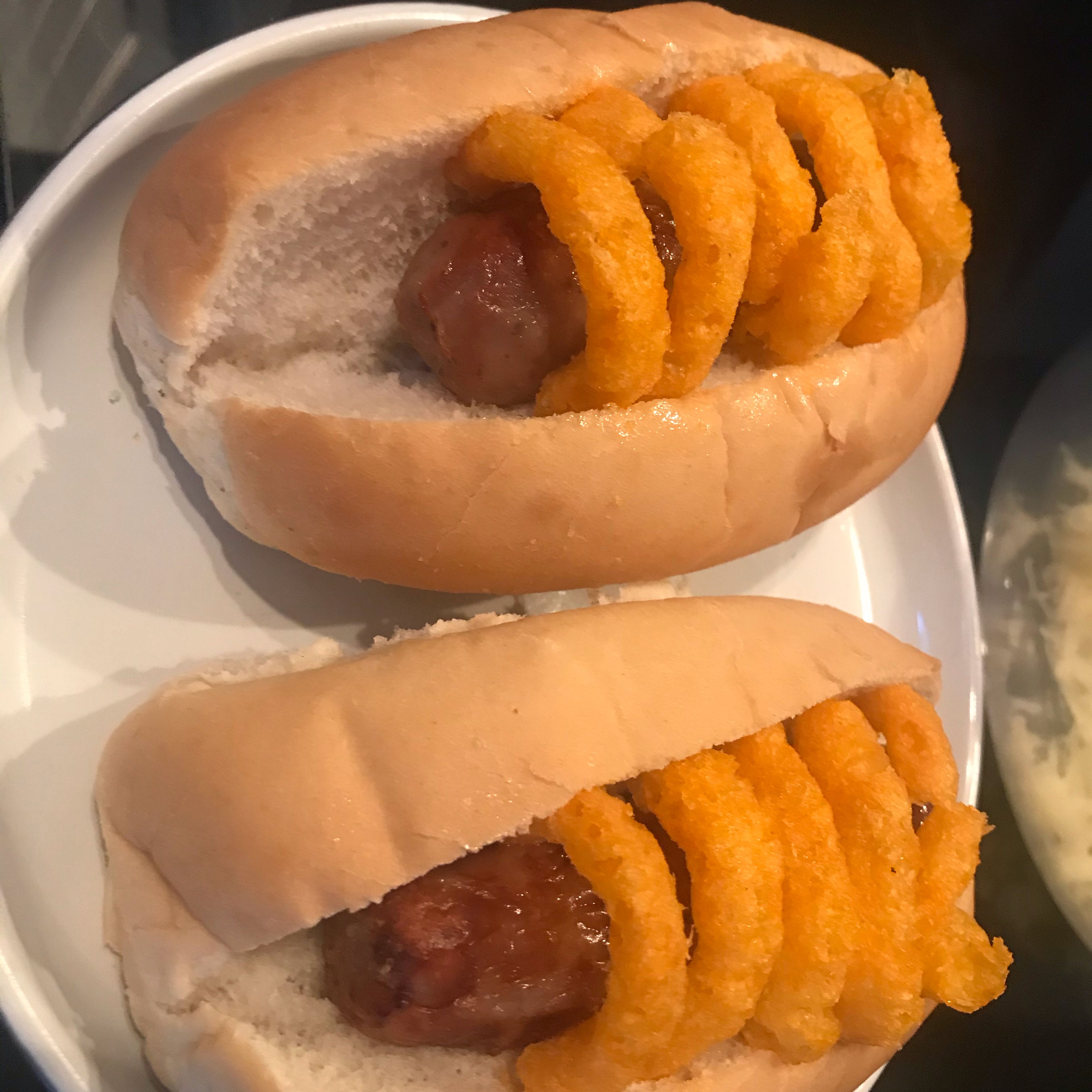Once cooked place the onion rings around the sausages. Spread each hot dog bun and place one sausage in each one.