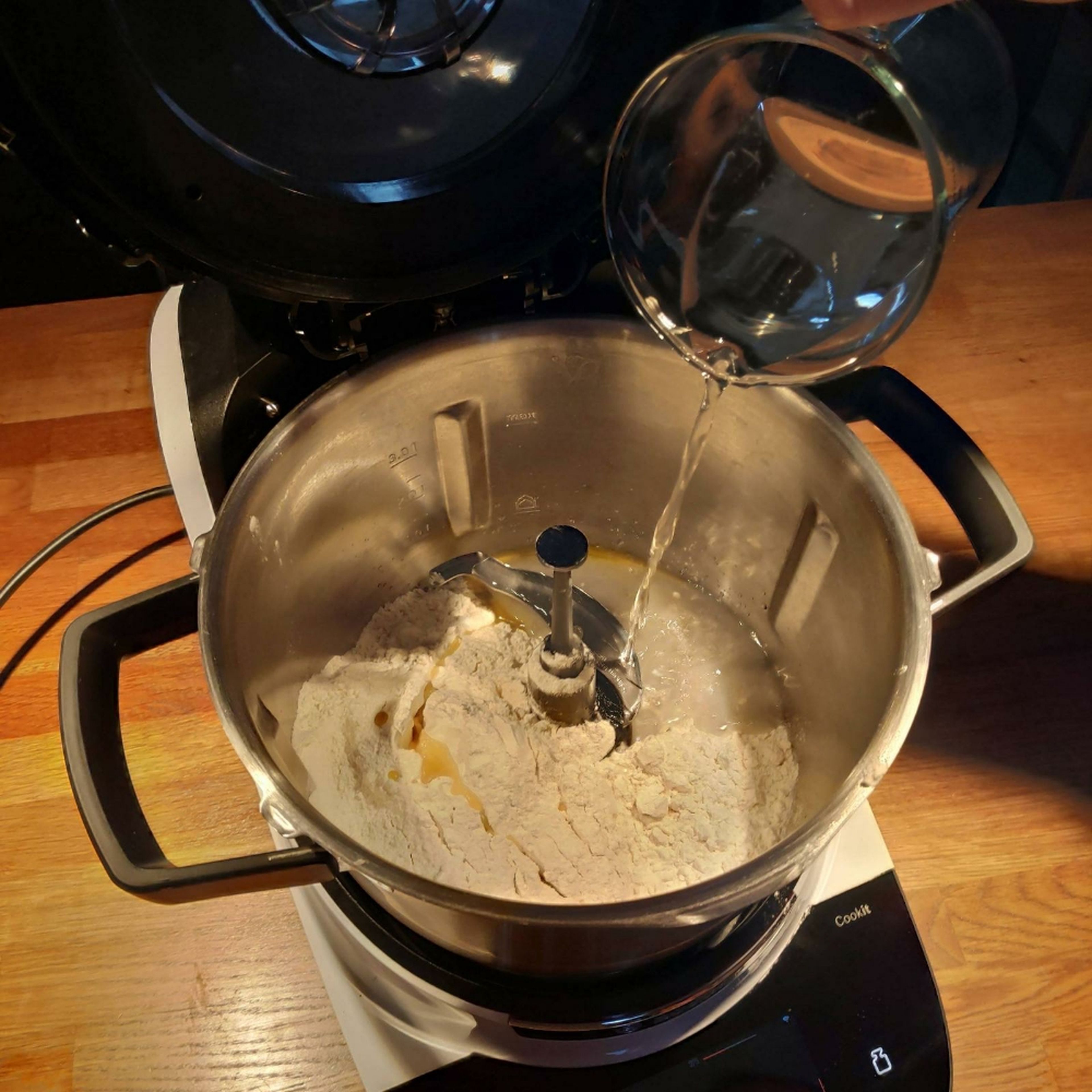 Das Universalmesser in den Cookit einsetzen. Mehl, Öl, Wasser und Salz in den Cookit geben und im Teigprogramm 1 für feste Teige bei geschlossenem Deckel kneten. Universalmesser entnehmen und den Teig anschließend in eine Schüssel umfüllen und 25 Minuten ruhen lassen.