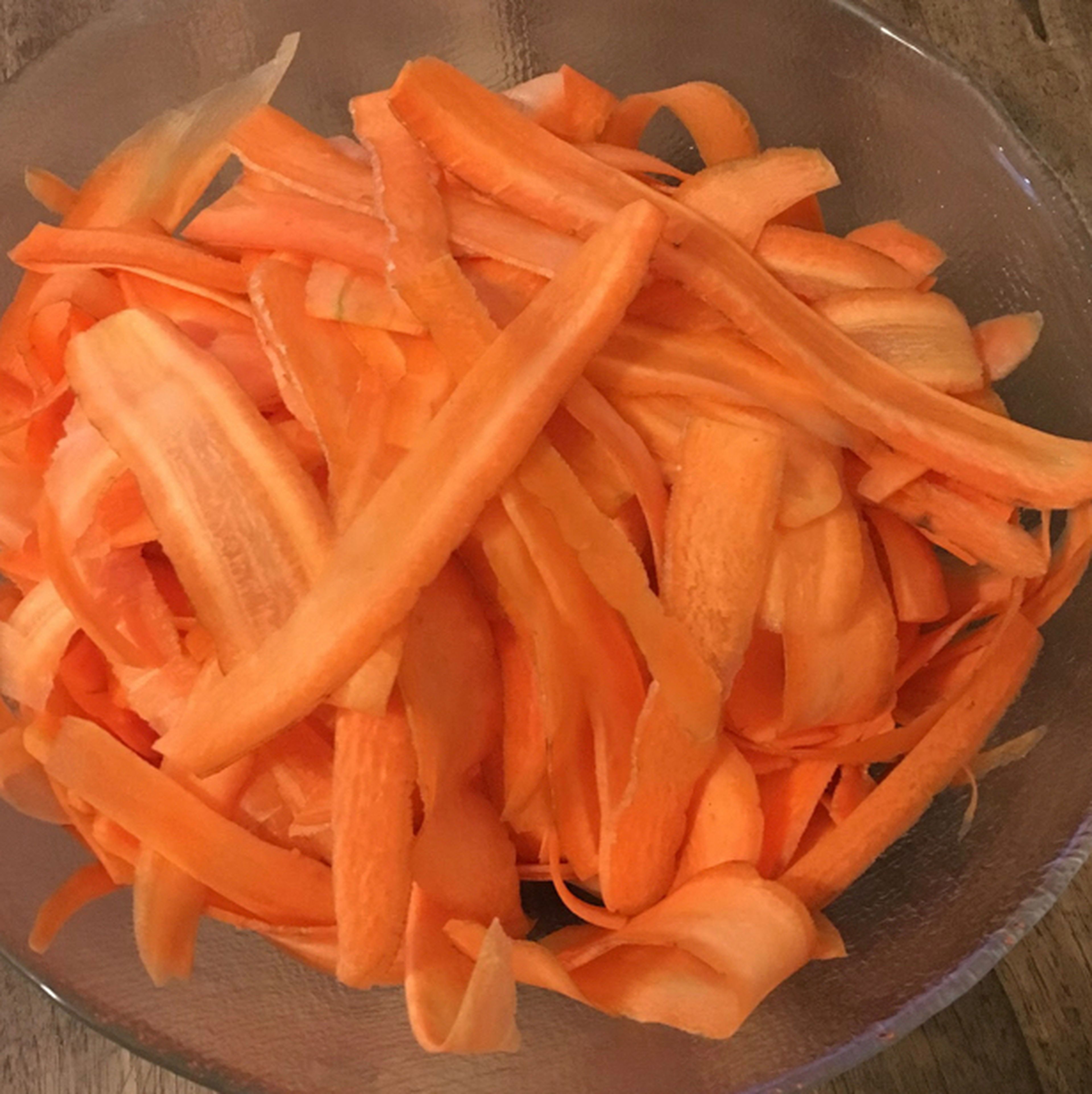 Zuerst Karotten schälen sowie die Enden abschneiden. Danach die Karotten längs in Scheiben „schälen“, sodass die Karotten alle gleich dünn und circa gleich lang sind.