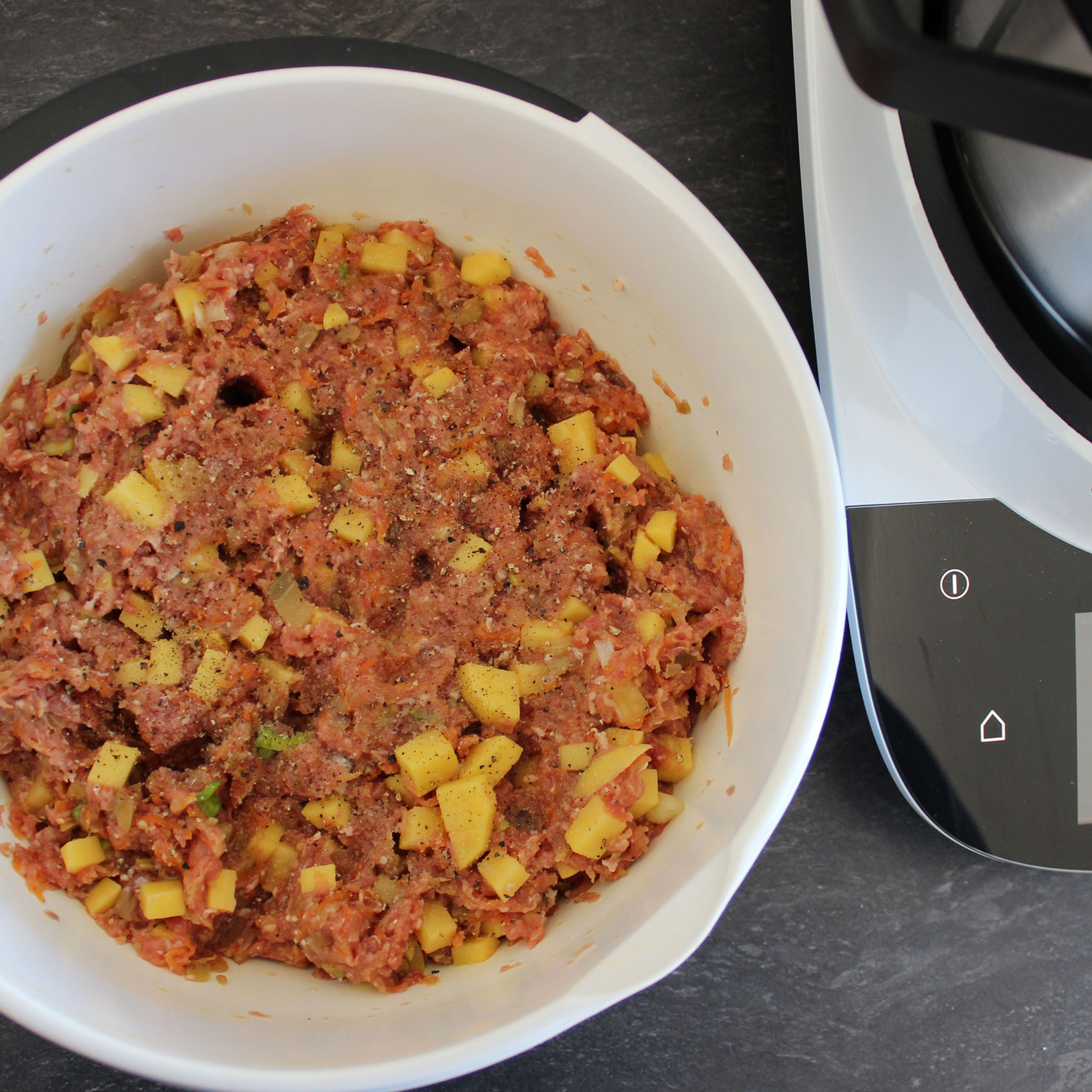 Cookit Wenderaspelscheibe in den Zerkleinerungsaufsatz einsetzen und Karotte fein raspeln (Cookit Wenderaspelscheibe | Stufe 5), entnehmen und beiseite stellen. Aubergine in 2 cm große Stücke würfeln, Kartoffeln in 1 cm große Stücke würfeln. Universalmesser einsetzen und Zwiebel vierteln, den Deckel schließen, den Messerbecher einsetzen und dann im Cookit zerkleinern (Cookit Universalmesser| Stufe 10 | 20 Sek.) und entnehmen. Mit dem Automatikprogramm "Gemüse anbraten" die Zwiebeln, Karotten- und Auberginenwürfel anbraten. Entnehmen und mit den Kartoffelwürfeln und dem Hackfleisch in eine Schüssel füllen. Zu einer homogenen Masse mischen/kneten und mit Salz, Pfeffer und Muskatnuss abschmecken.