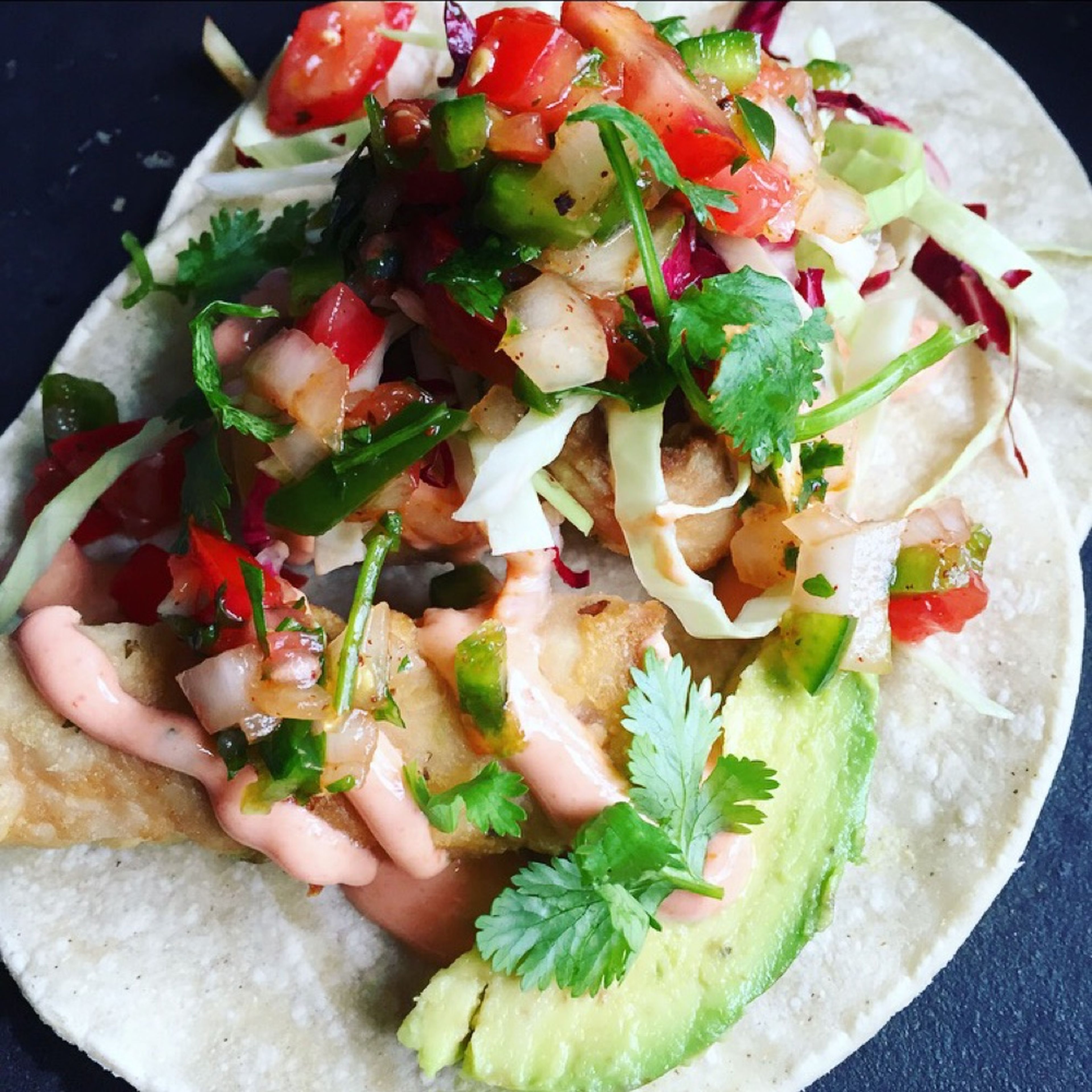 Warm corn tortillas in another frying pan. To assemble, lay 3 pieces of fish over the tortillas. Drizzle the Sriracha sauce over, then top with sliced avocado, salsa, shredded cabbage and radicchio, and some lime juice. Serve warm!