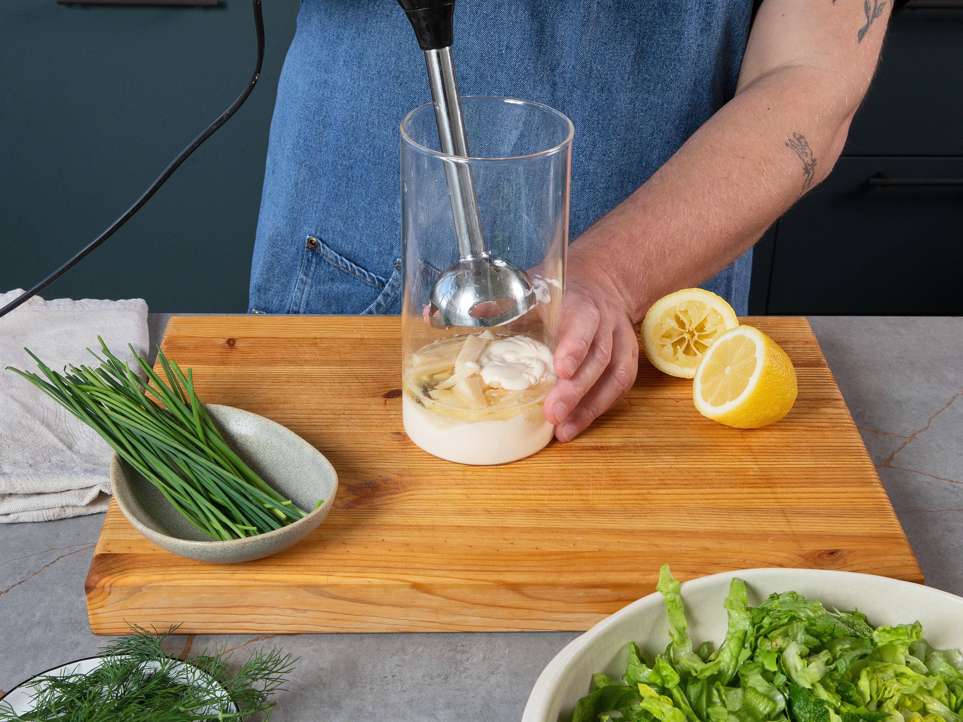 Für das Caesar-Dressing die Mayonnaise mit Worcestershire Sauce, Sardellen, Parmesan, Senf, etwas Zitronensaft, Zitronenzeste und Knoblauch in ein hohes Gefäß geben und mit einem Pürierstab zu einer glatten Soße pürieren. Anschließend das Dressing mit Salz, Pfeffer und optional mehr Zitronensaft abschmecken. Zitrone in Spalten schneiden. Den Römersalat in feine Streifen schneiden. Den Salat in einer Schüssel mit dem Dressing vermischen. Dann den Salat auf den Hähnchen-Schnitzeln anrichten und mit Zitronenspalten und frischen Kräutern anrichten.