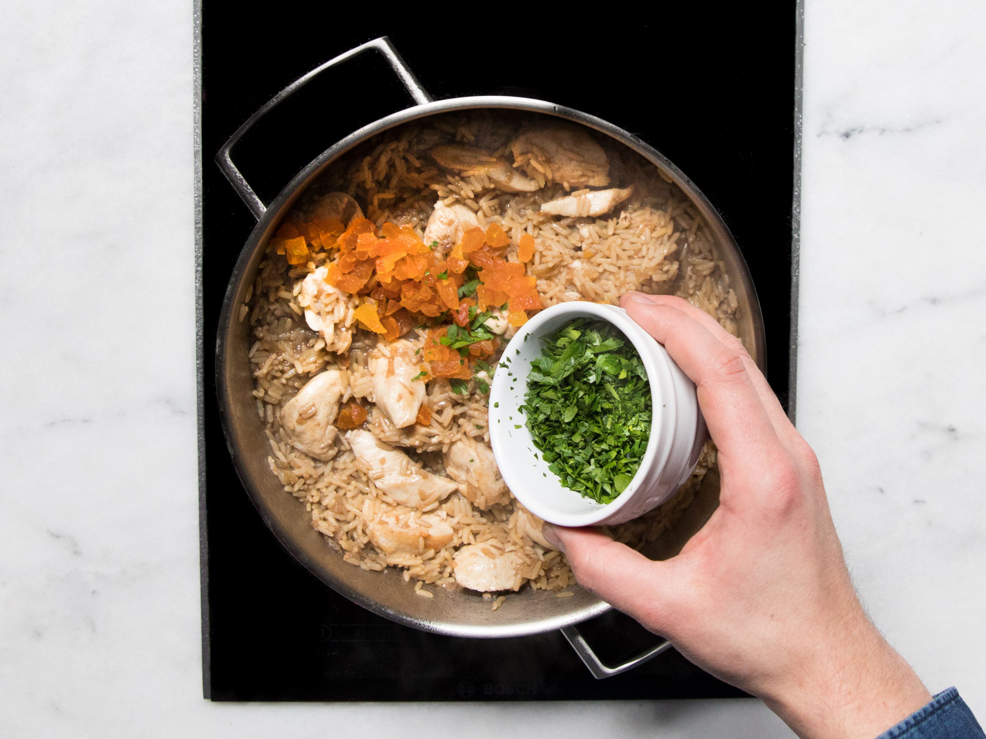 Once the rice is done, remove the lid and add chicken back to the frying pan. Heat for approx. 2 min., then add dried apricots and chopped parsley, and stir to combine. Serve pilaf with yogurt on top, and sprinkle with sliced almonds, parsley, and dukkah. Enjoy!