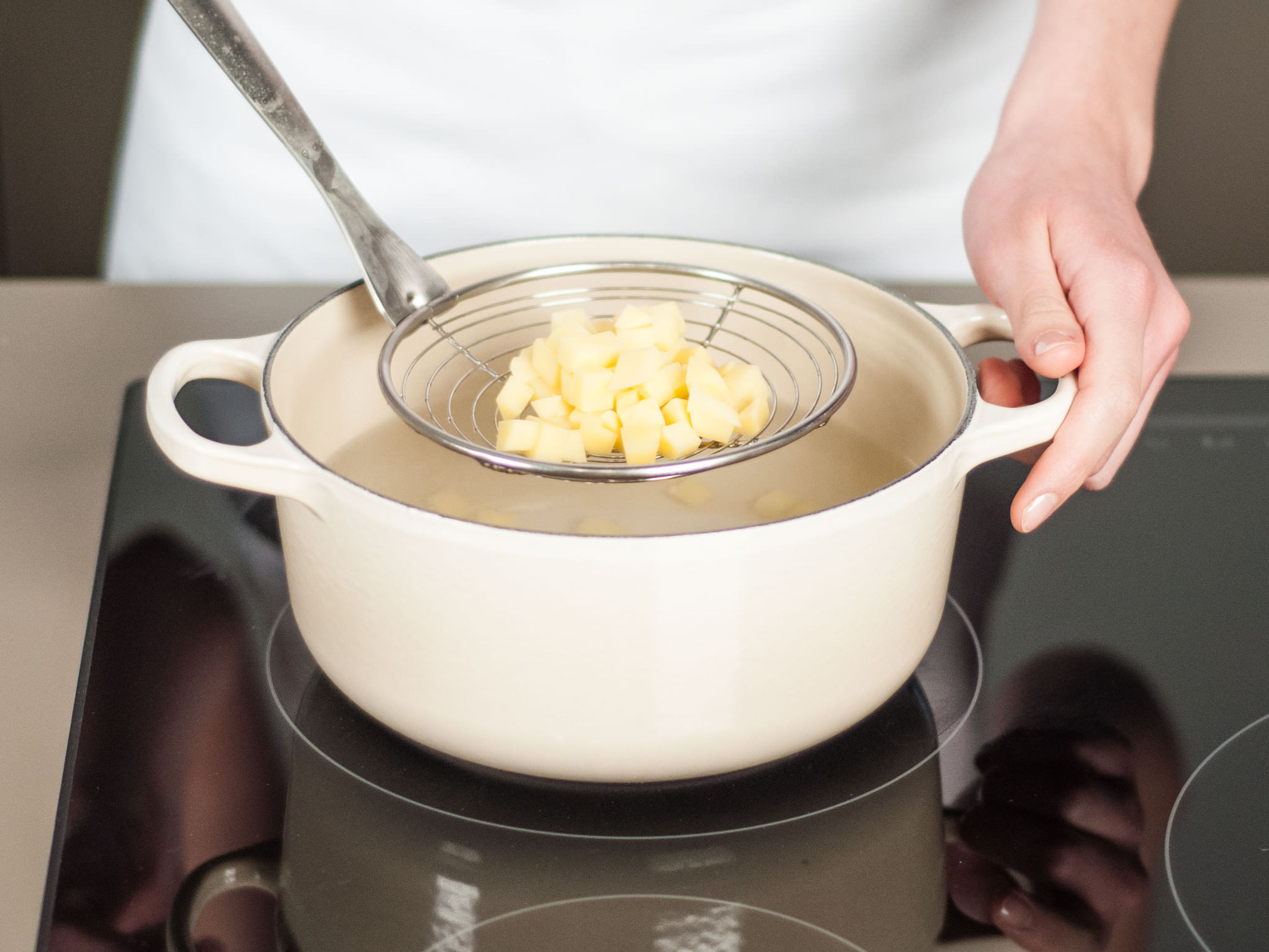 In einem weiteren Topf leicht gesalzenes Wasser zum Kochen bringen. Kartoffelwürfel hinzugeben und ca. 10 – 13 Min. gar kochen. Dann aus dem Wasser nehmen und beiseitestellen.