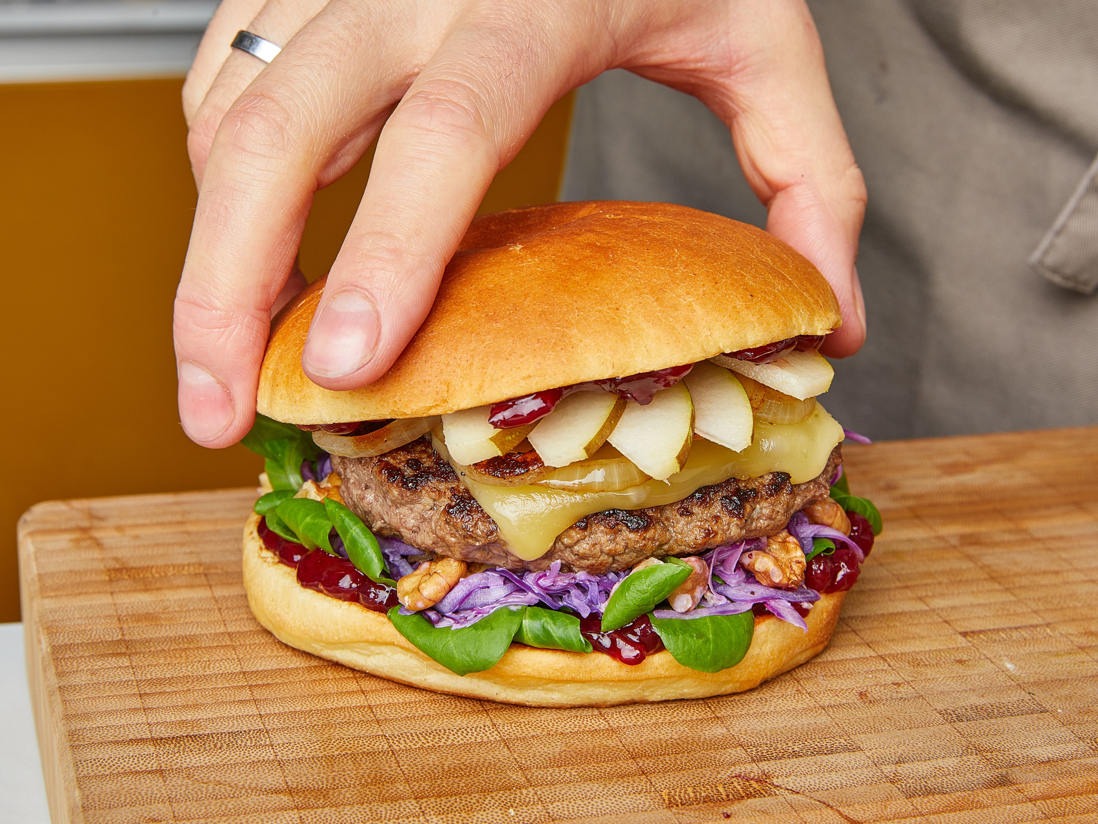 Spread a dollop of lingonberry jam on the toasted cut surfaces of all burger buns. Top buns with patties, onions, lettuce, red cabbage, and pear slices, then cover with the other half of burger buns. Serve immediately.
