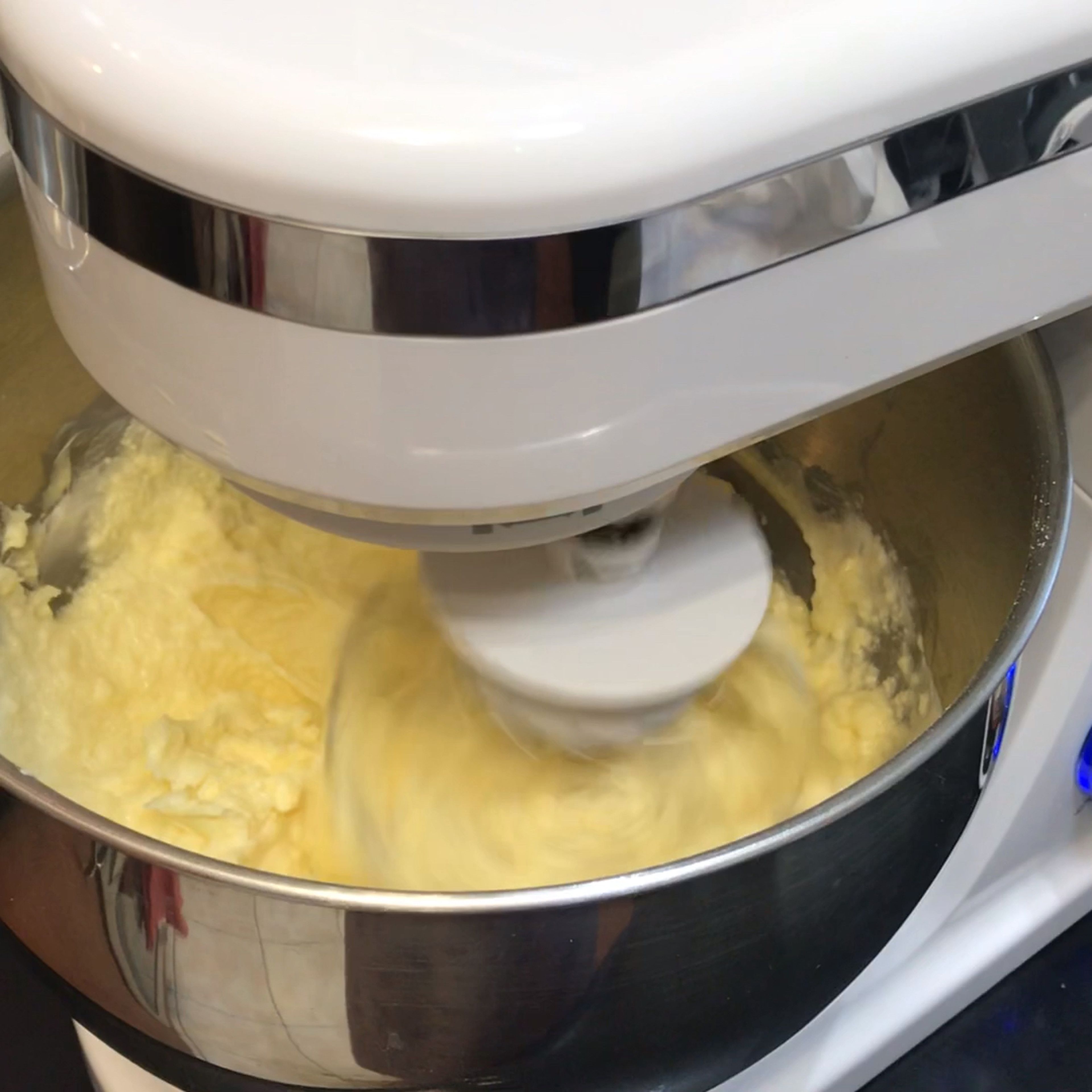 Add in your softened butter in chunks and whip on high for 8-10 minutes until it's very white, light and shiny. It may look curdled and yellow at first, this is normal. Keep whipping.