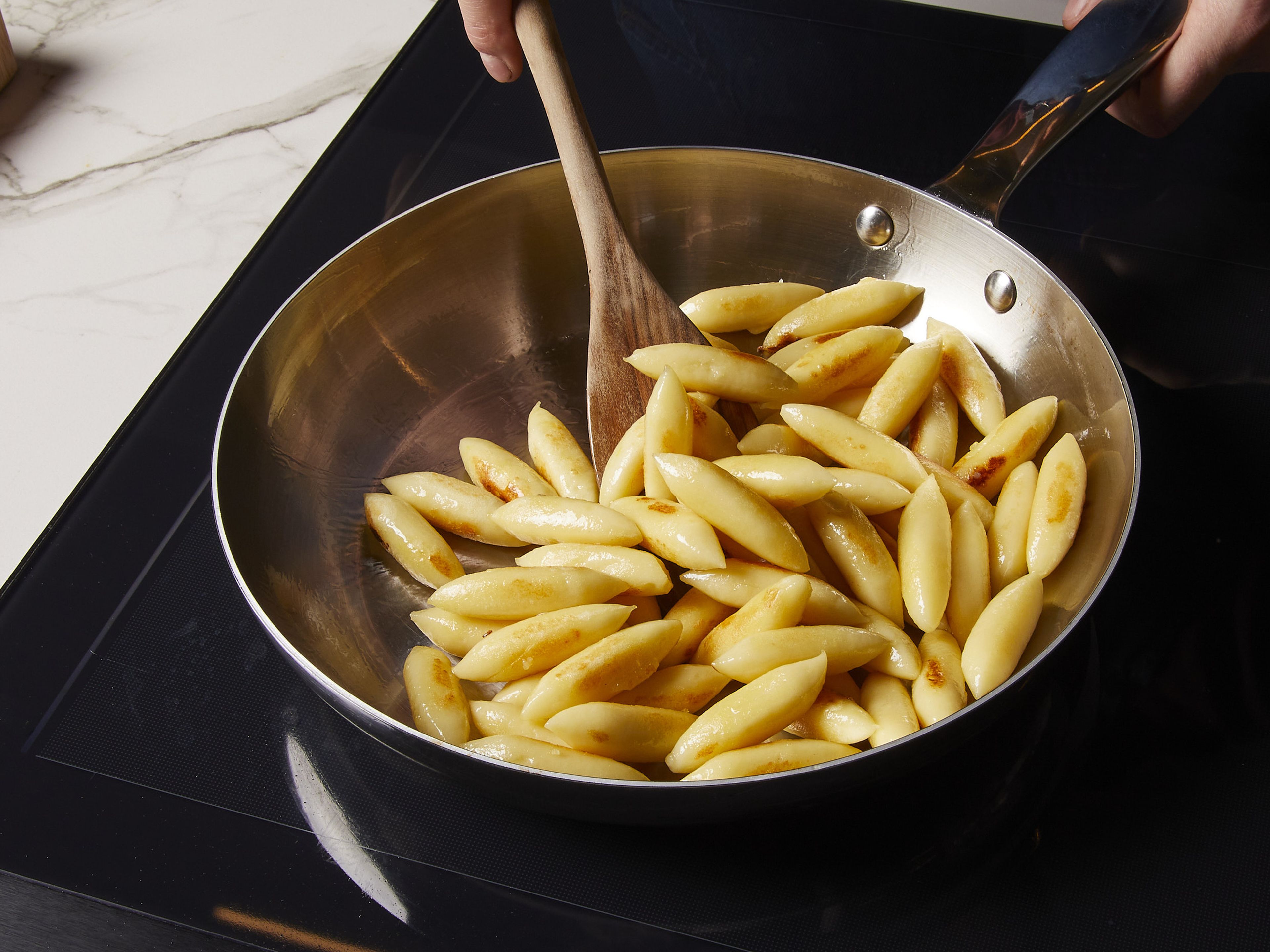 Heat oil in a pan. Fry the German gnocchi until golden brown and crispy. Then, remove from the pan and set aside.