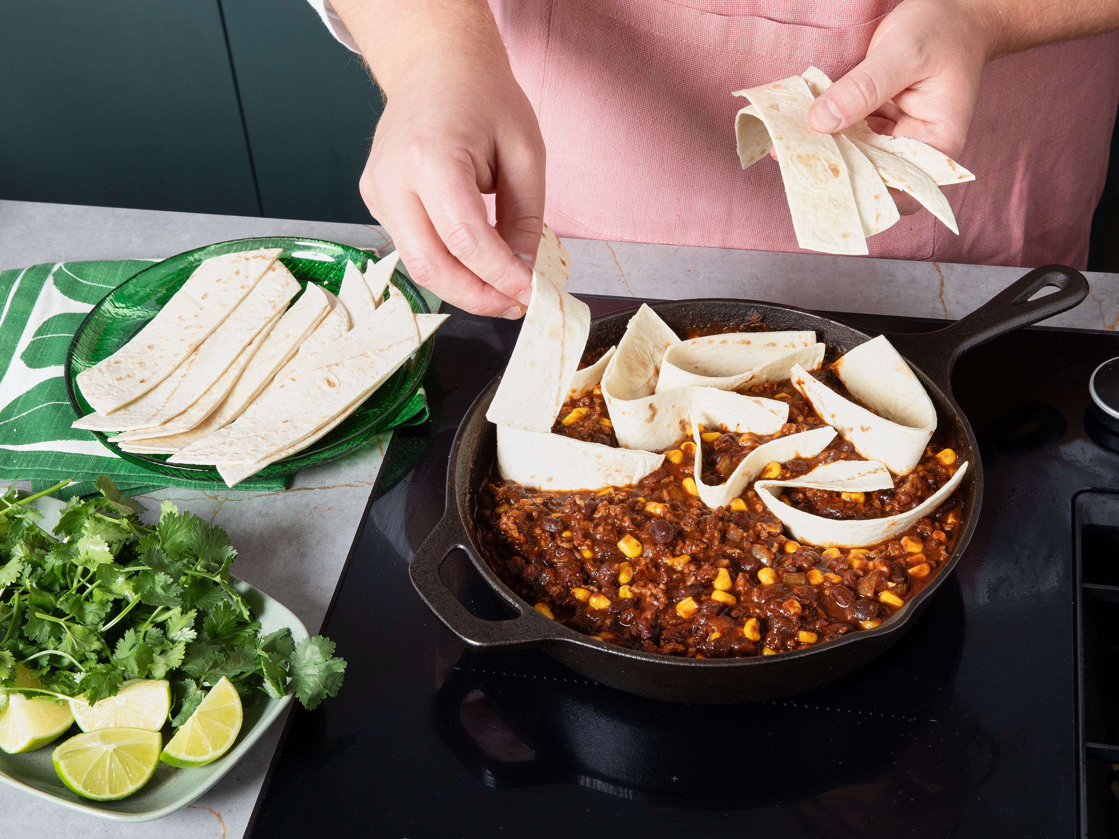 Paprikapulver, Kreuzkümmel, Oregano und Chilipulver in die Pfanne geben und kurz mitrösten. Die passierten Tomaten, Kakaopulver, Brühe, schwarzen Bohnen und den Mais hinzufügen und alles gut verrühren. Die Tortillas in mundgerechte Stücke schneiden und unterheben. Die Mischung für ca. 8–10 Min. köcheln lassen, bis die Sauce leicht eindickt und die Tortilla Stücke weich werden.