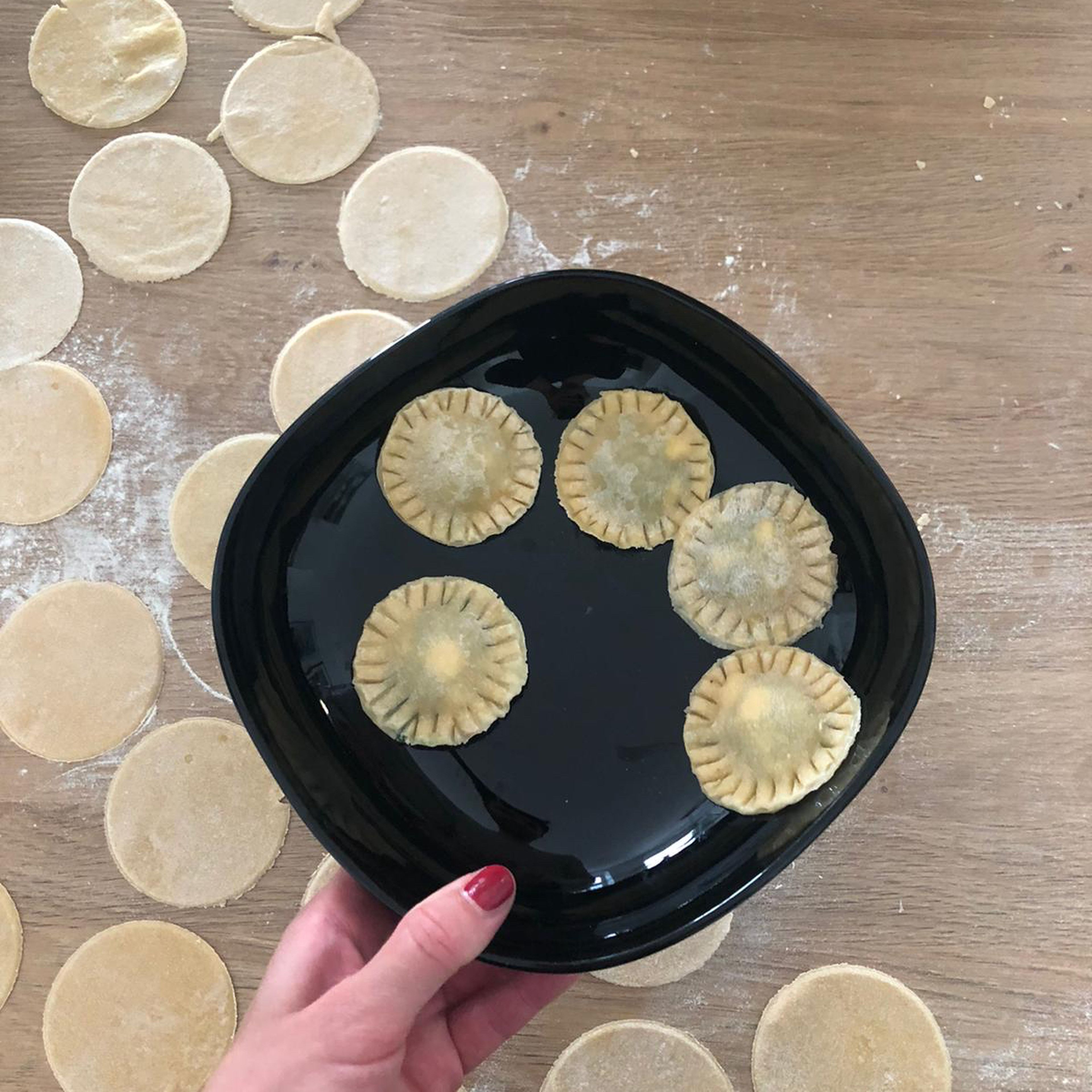 Den Teig nun hauchdünn mit etwas Mehl ausrollen und kreisrunde Stücke ausstechen. Die Kreise am Rand mit einem in Wasser getunkten Pinsel befeuchten. Mit dem Spinat- Feta Gemisch füllen und an der Seite mit einer Gabel eindrücken um die Pasta zu verschließen.