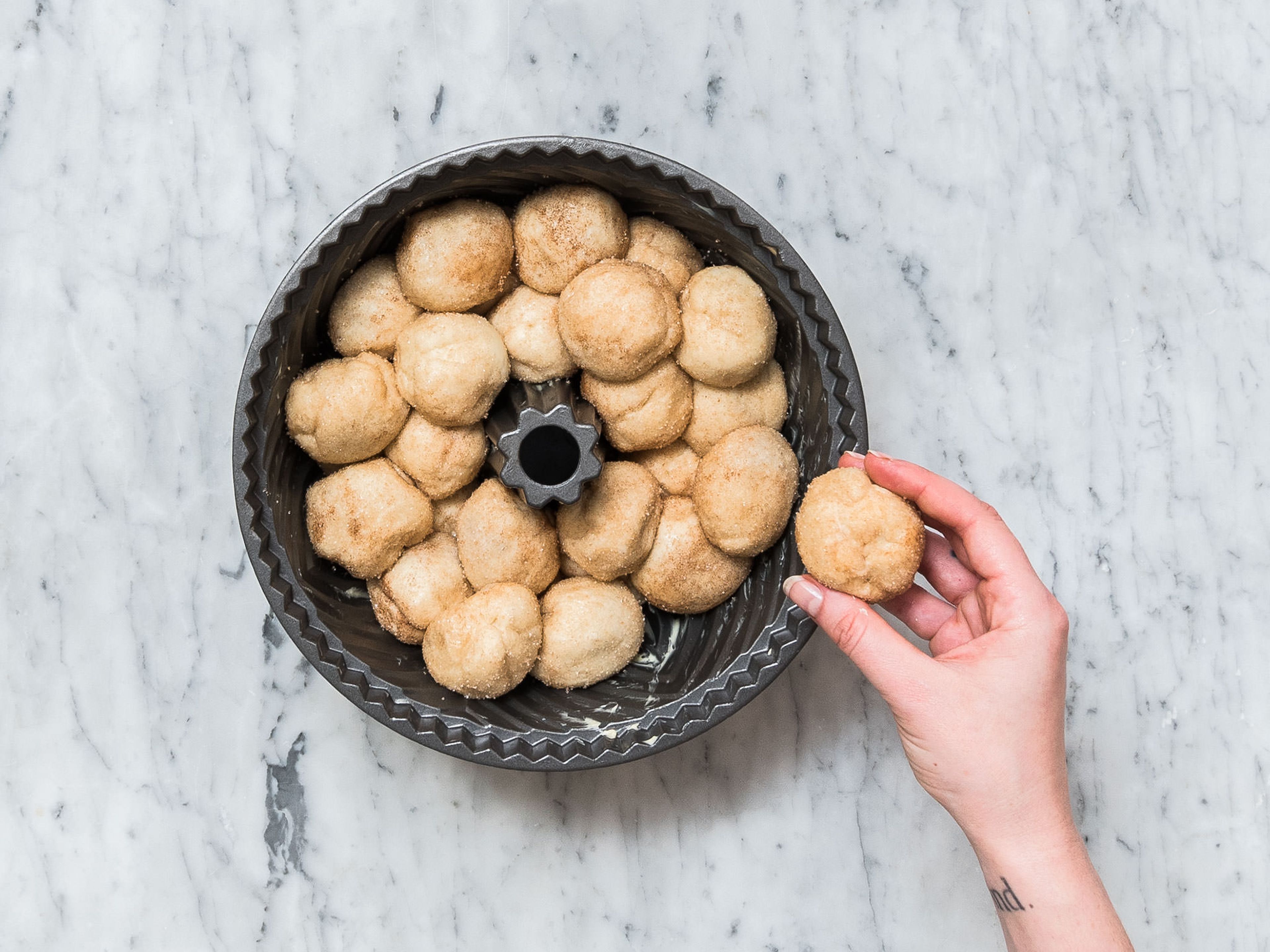 Toss the balls in the sugar-cinnamon mixture and stack into a greased bundt pan. Bake at 175°C/ 350°F for approx. 35 – 40 min. If the monkey bread gets too dark, cover with aluminum foil. After baking allow to cool for a few minutes, turn onto a plate.