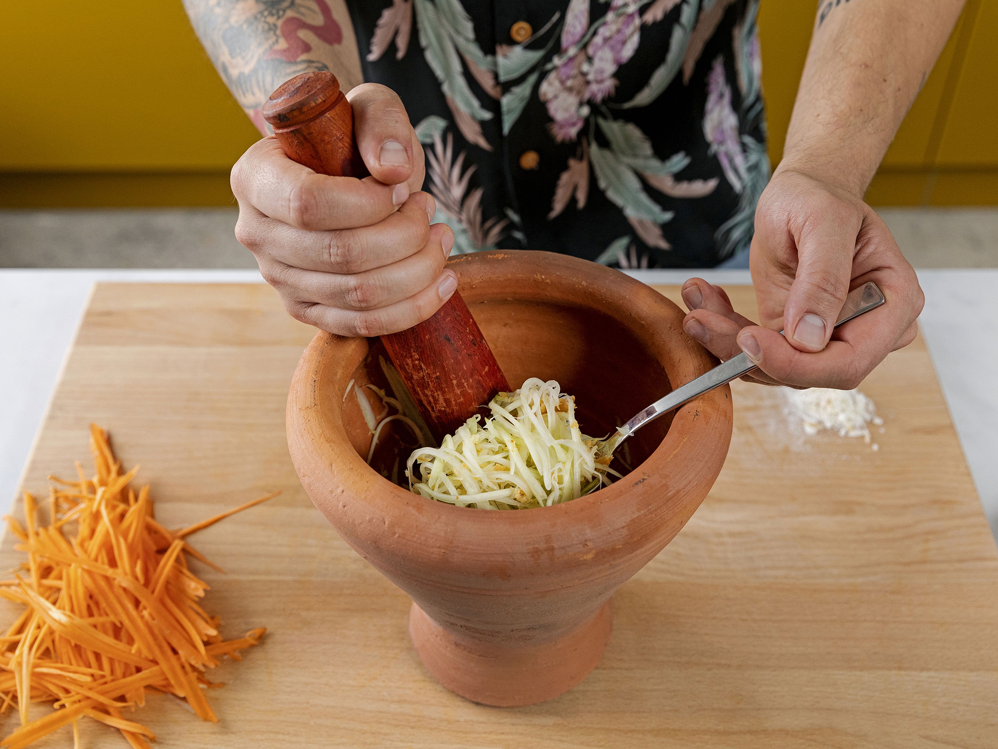 Add the garlic, chilli, and drained shrimp to a mortar and pestle and pound until chilis are broken apart. Now add one-third of the papaya and gently pound until papaya is tender but not mushy.