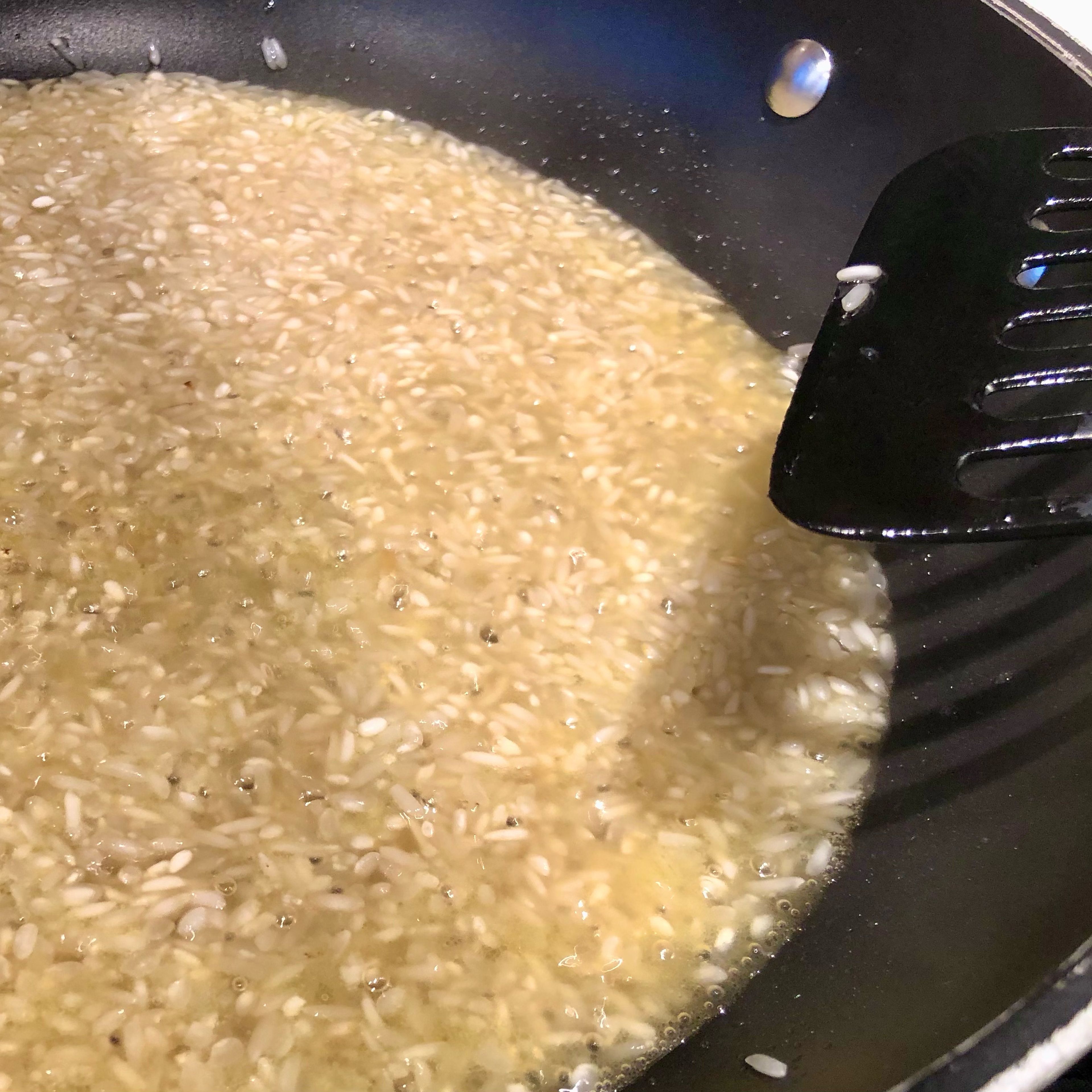 In einer weiten Pfanne Butter(schmalz) zerlassen, den (ungewaschenen) Risottoreis zugeben und etwa eine Minute anbraten, dabei rühren bzw. wenden. Mit dem Weißwein ablöschen und etwa 1 TL Salz zugeben - die Salzmenge auf die Salzigkeit der Brühe abstimmen! Wenn der Wein verkocht ist, wieder rühren und einen ersten Teil der Brühe angießen, etwa so viel, dass der Reis gerade so bedeckt ist. Dabei ist die Temperatur eher hoch, so dass es in der Pfanne immer siedet bis blubbert.