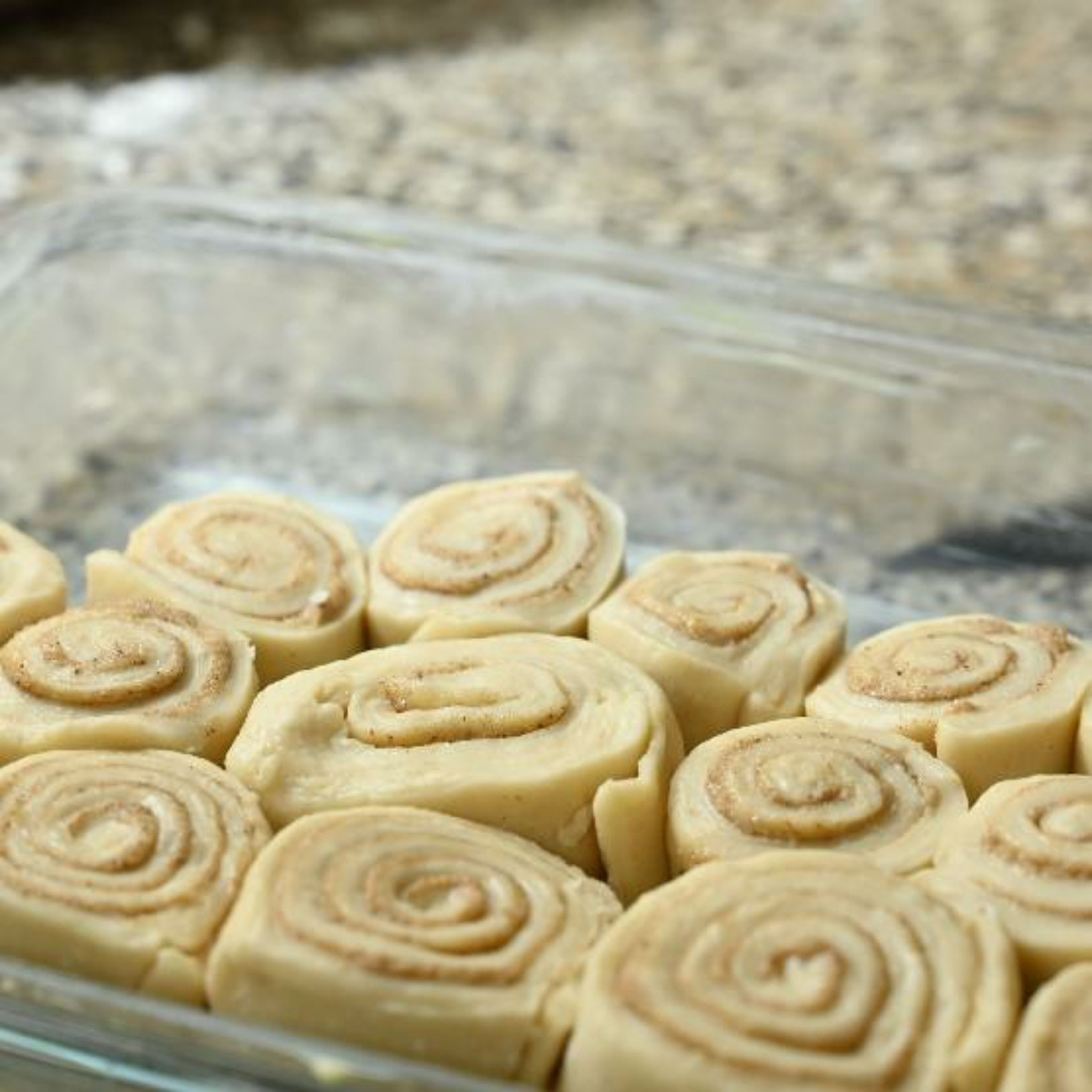 Cut the log into small pieces. Butter a non-stick baking tray and place the cut cinnamon rolls into the prepared tin.