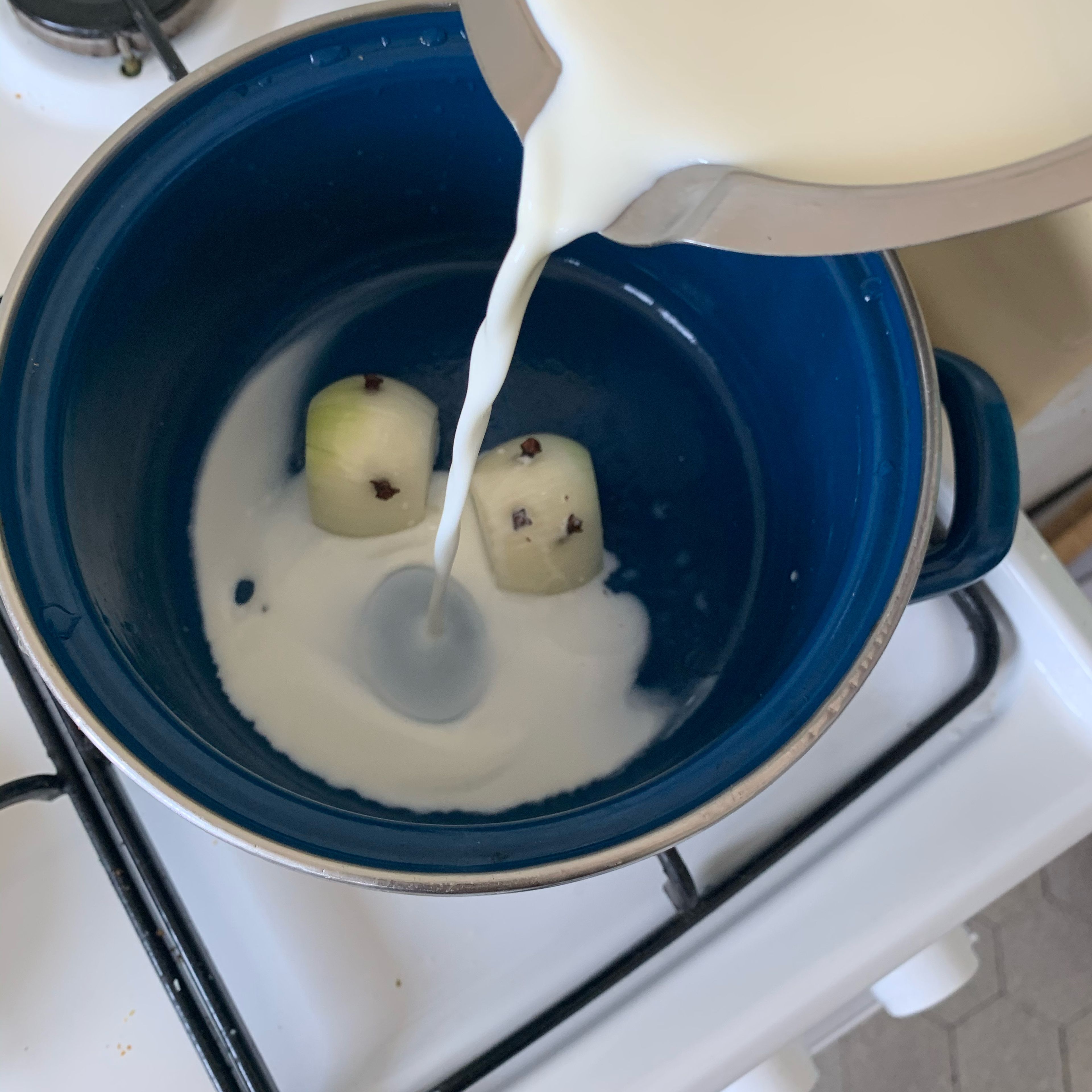 Peel a small or half an onion and spike it with cloves. Bring the milk with the spiked onion to a boil and let it rest next to the heat for approx. 10 min. Then remove onion from the milk.