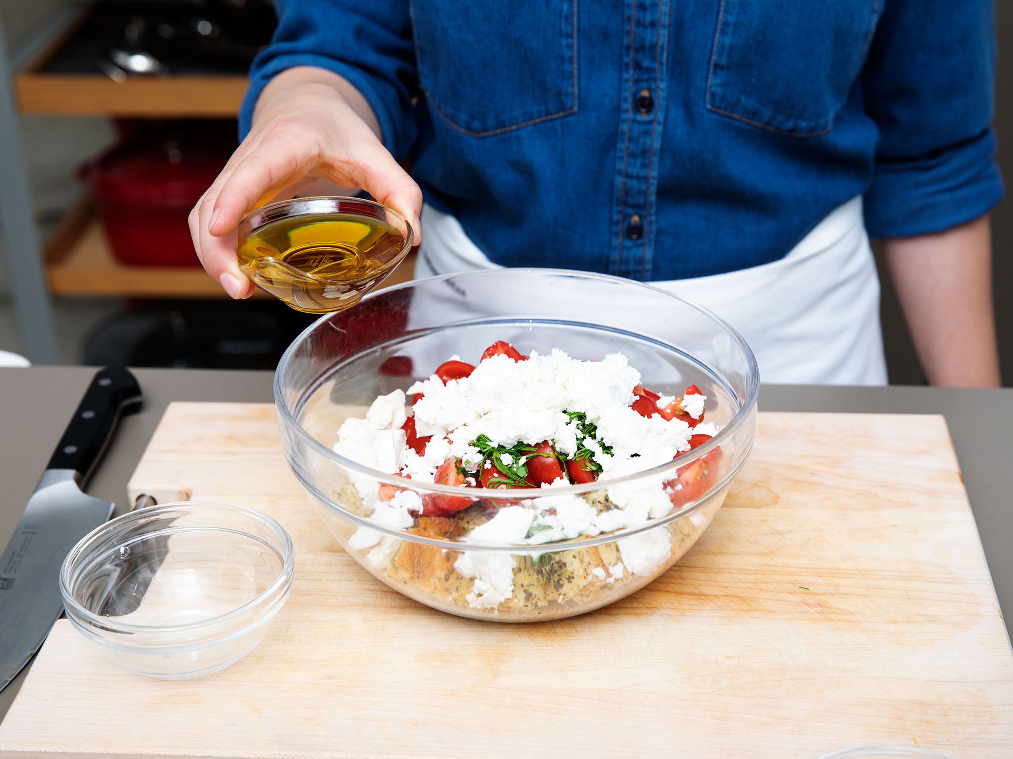 To make the tomato and bread salad, quarter the cherry tomatoes and place into a serving bowl. Slice basil into thin ribbons, crumble in the feta cheese, add olive oil, and season with salt and pepper. Toss well and set aside.