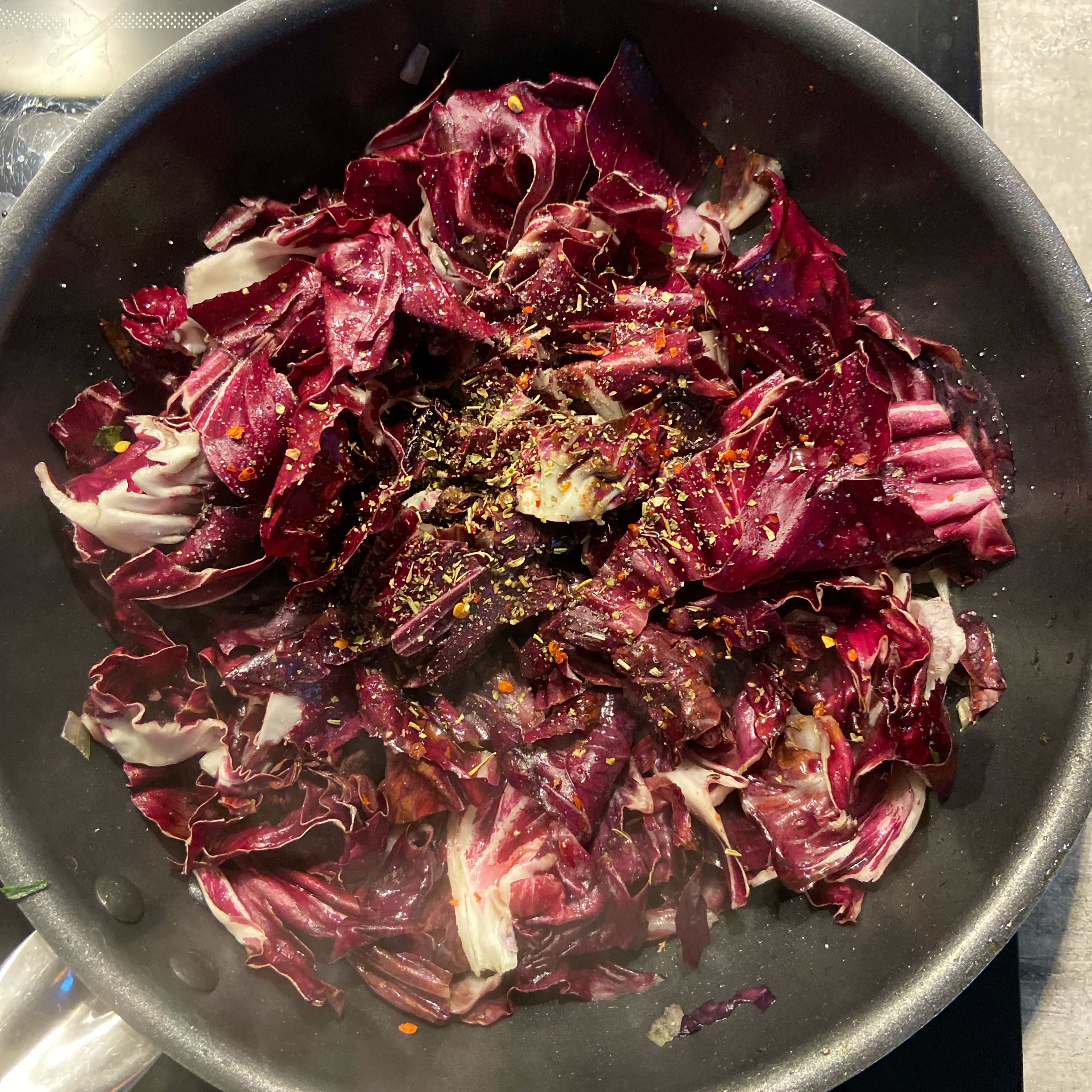 Add oil and half red onion to a frying pan. When golden, add the sliced radicchio and let it cook for a few minutes until it starts becoming softer. Then add the red wine, salt and pepper, and keep cooking for around 10 minutes.