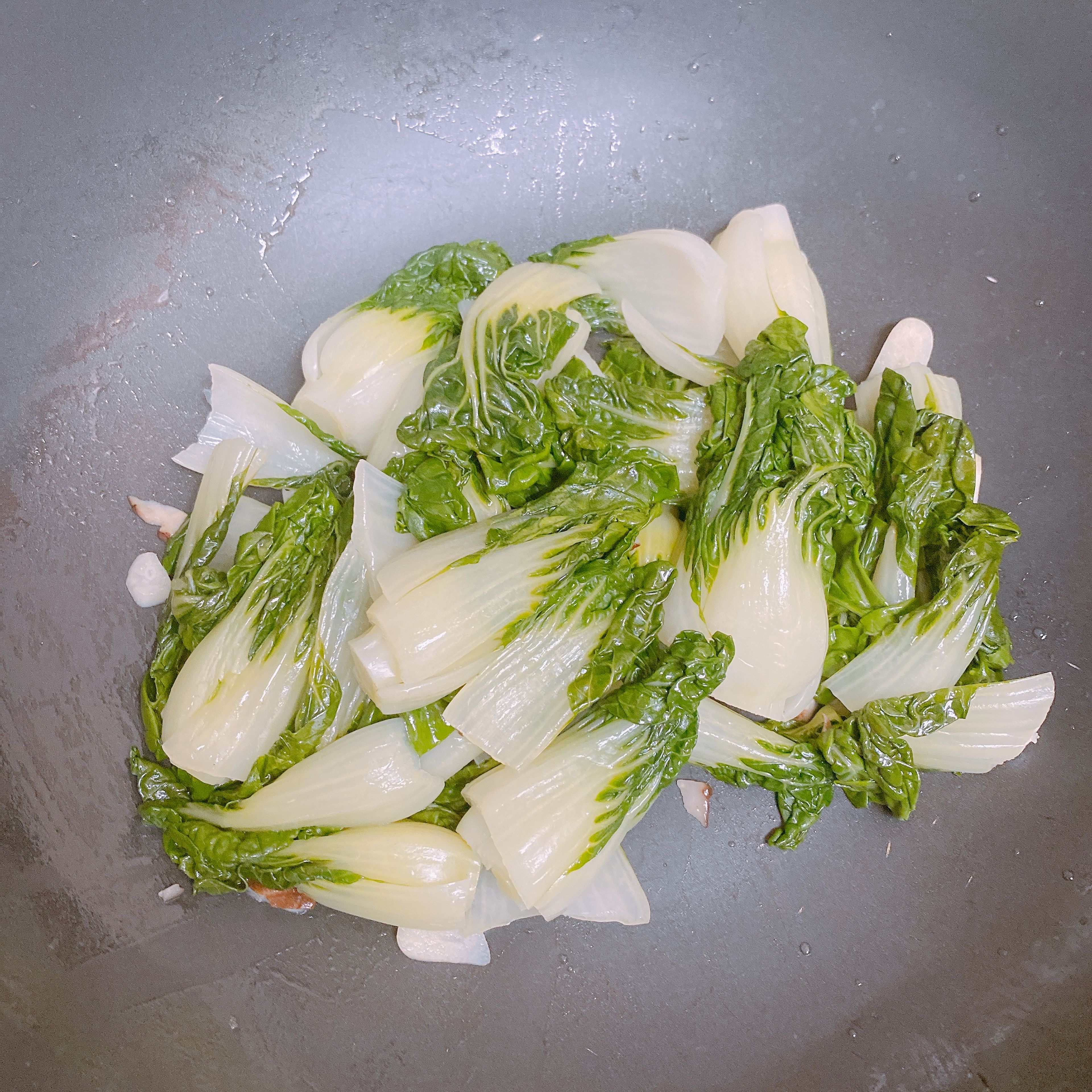 Add half of the oil and turn on the stove. When the oil is heated, add half of the garlic (garlic mix if you have mushroom chips), fry for a few seconds until you can smell the garlic, and add the baby bok choy. Fry for a minute, turn off the stove if you want, and scoop them all out to the plate/big bowl in which you want to serve the dish.