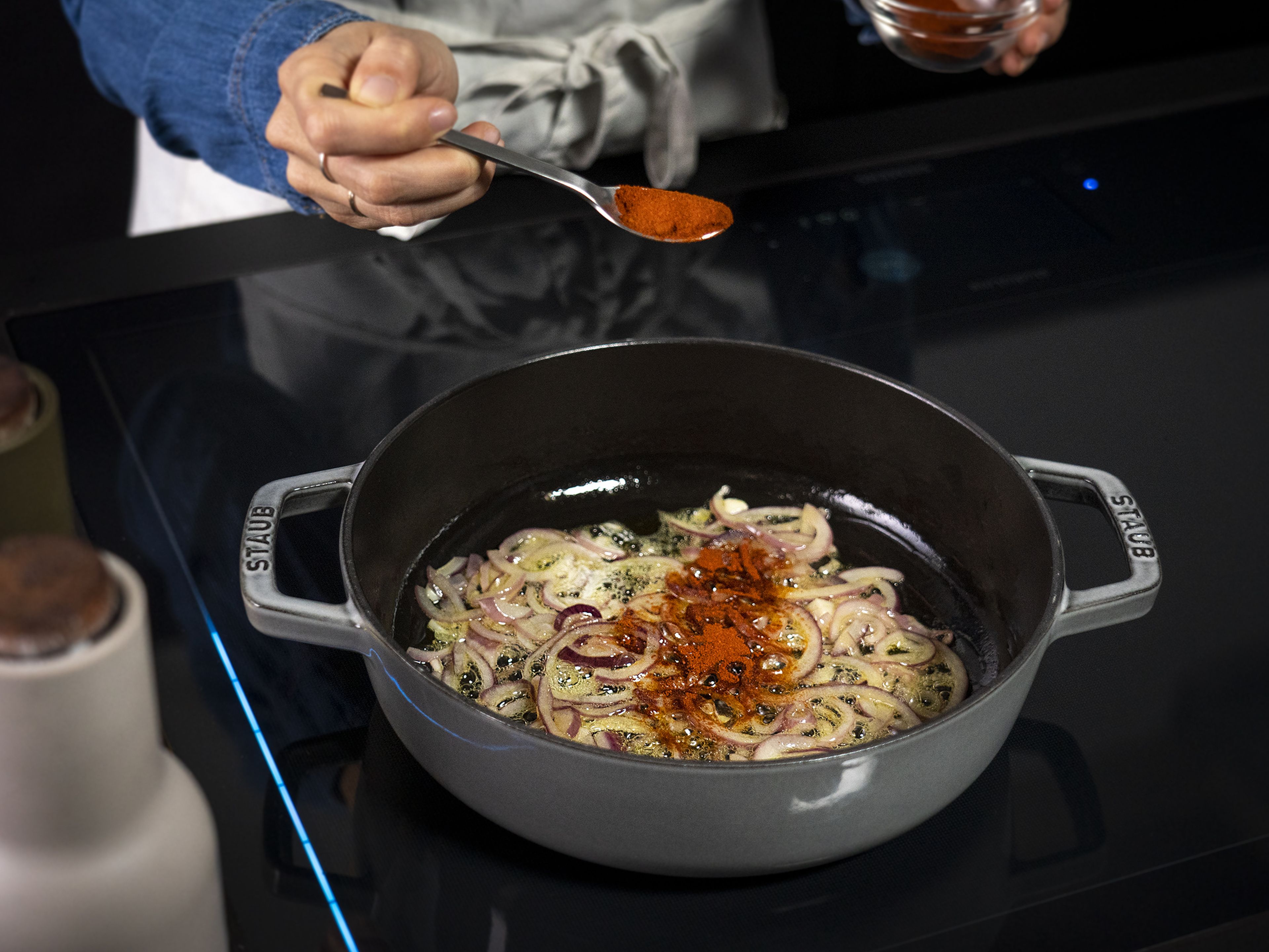 Set a pan with a lid over medium-low heat and add some olive oil. Add chopped onion and sauté for approx. 5 min., or until onion is translucent. Add half the paprika and stir everything together for approx. 1 min.