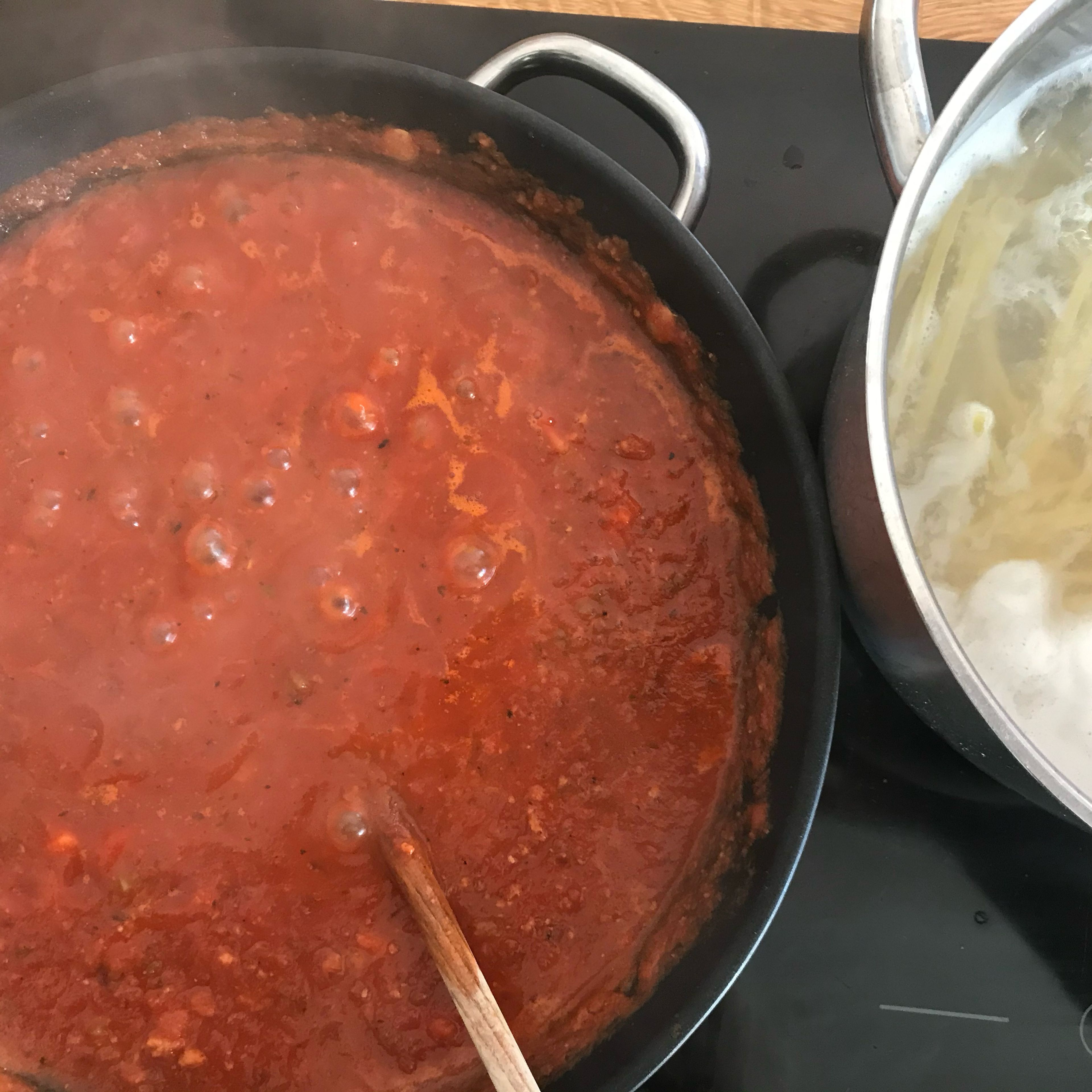 Tomaten entstrunken und fein püriert mit in die Pfanne geben. Mindestens 20 min köcheln lassen. Währenddessen Spaghetti in großem Kochtopf mit Wasser und etwas Salz al dente kochen.