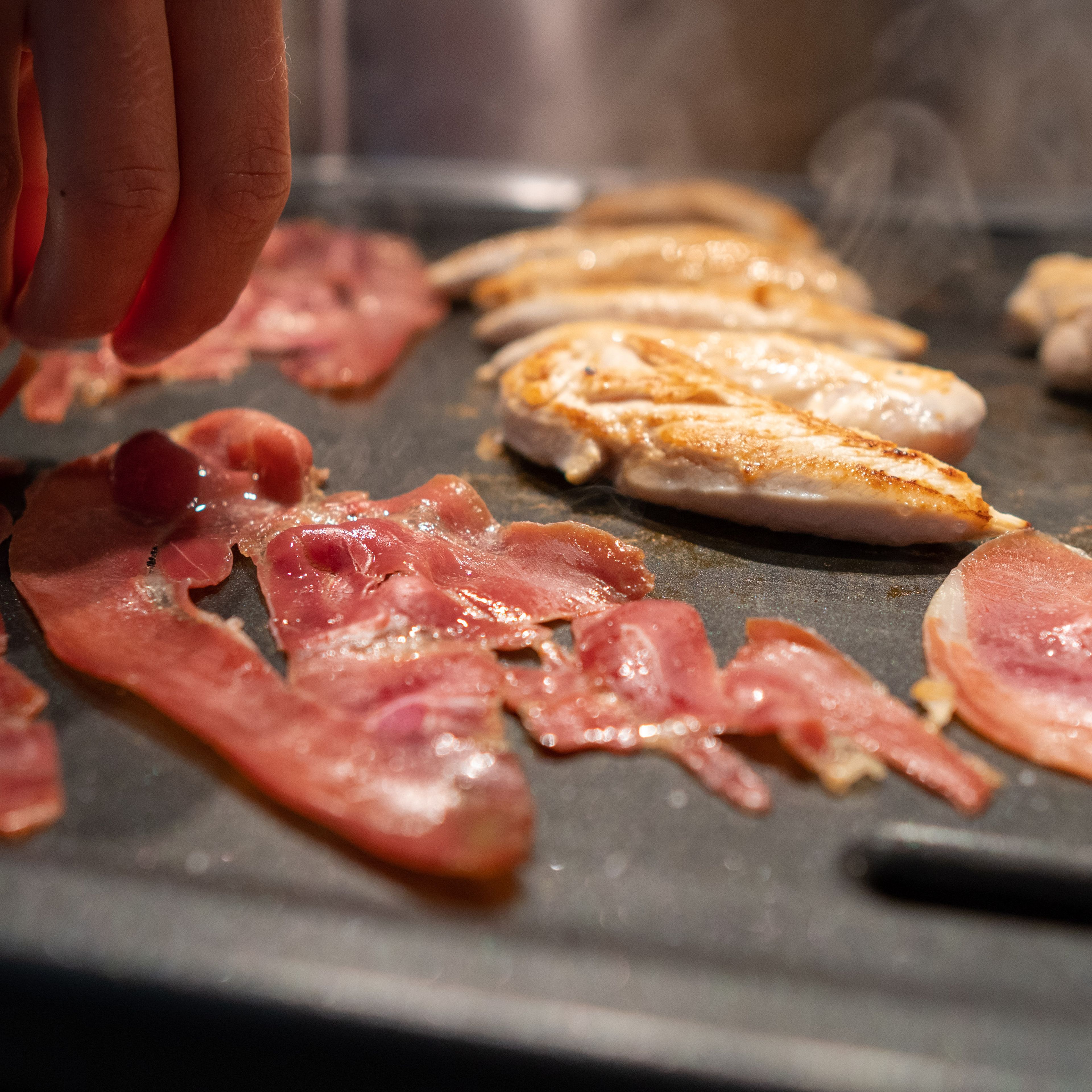 Hähnchenstreifen, Bacon und Spiegelei in der Pfanne goldbraun anbraten. Hähnchenstreifen mit Salz und Pfeffer würzen.