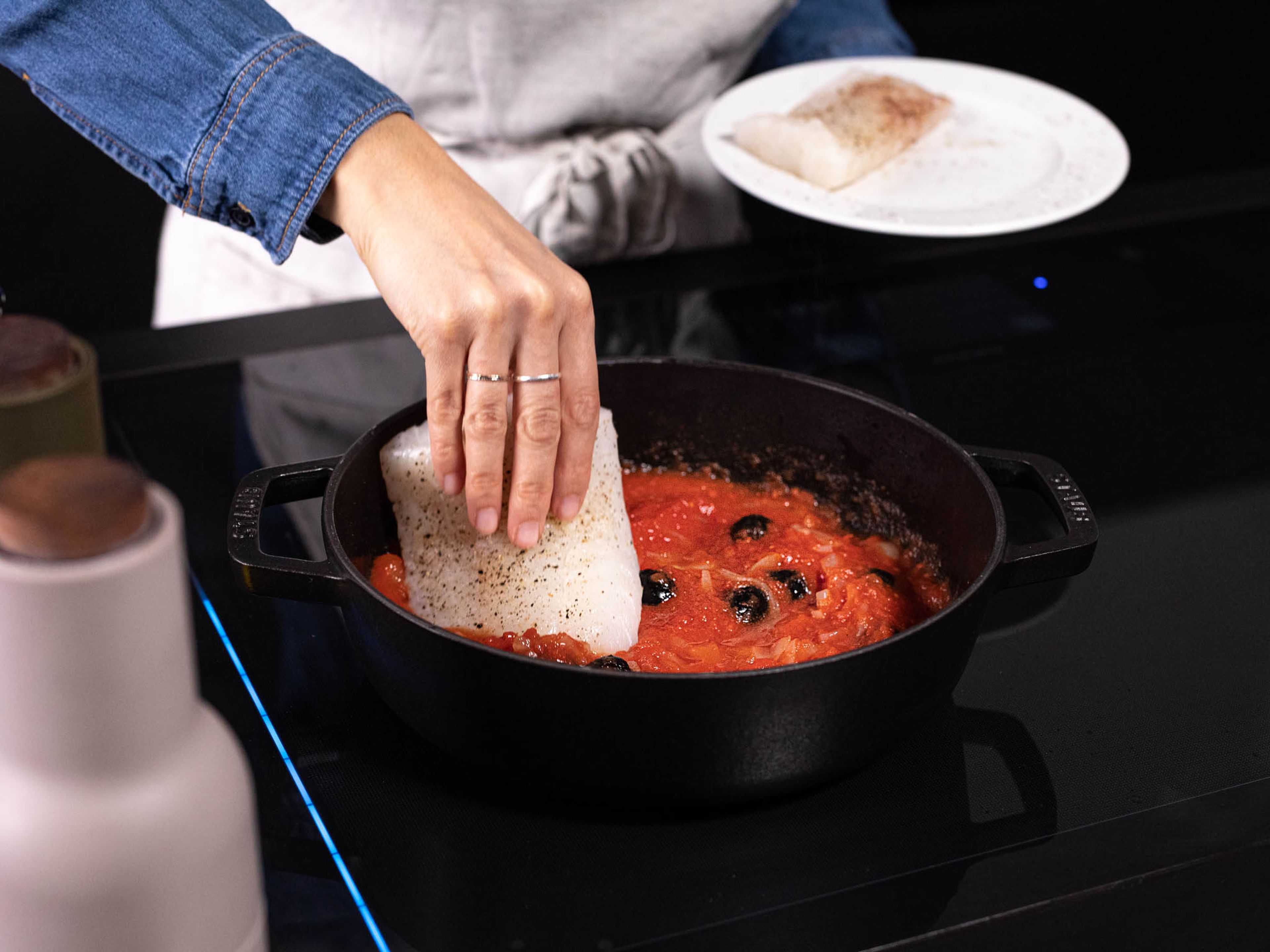 Transfer fish to the pan and cover each fillet with some of the tomato sauce. Lower heat to medium-low, partially cover the pan with a lid, and let simmer for approx. 8 min., or until fish is cooked through. Once the filet flakes with a gentle push, the fish is cooked. Serve immediately topped with fresh basil, chili flakes, and toasted bread. Enjoy!