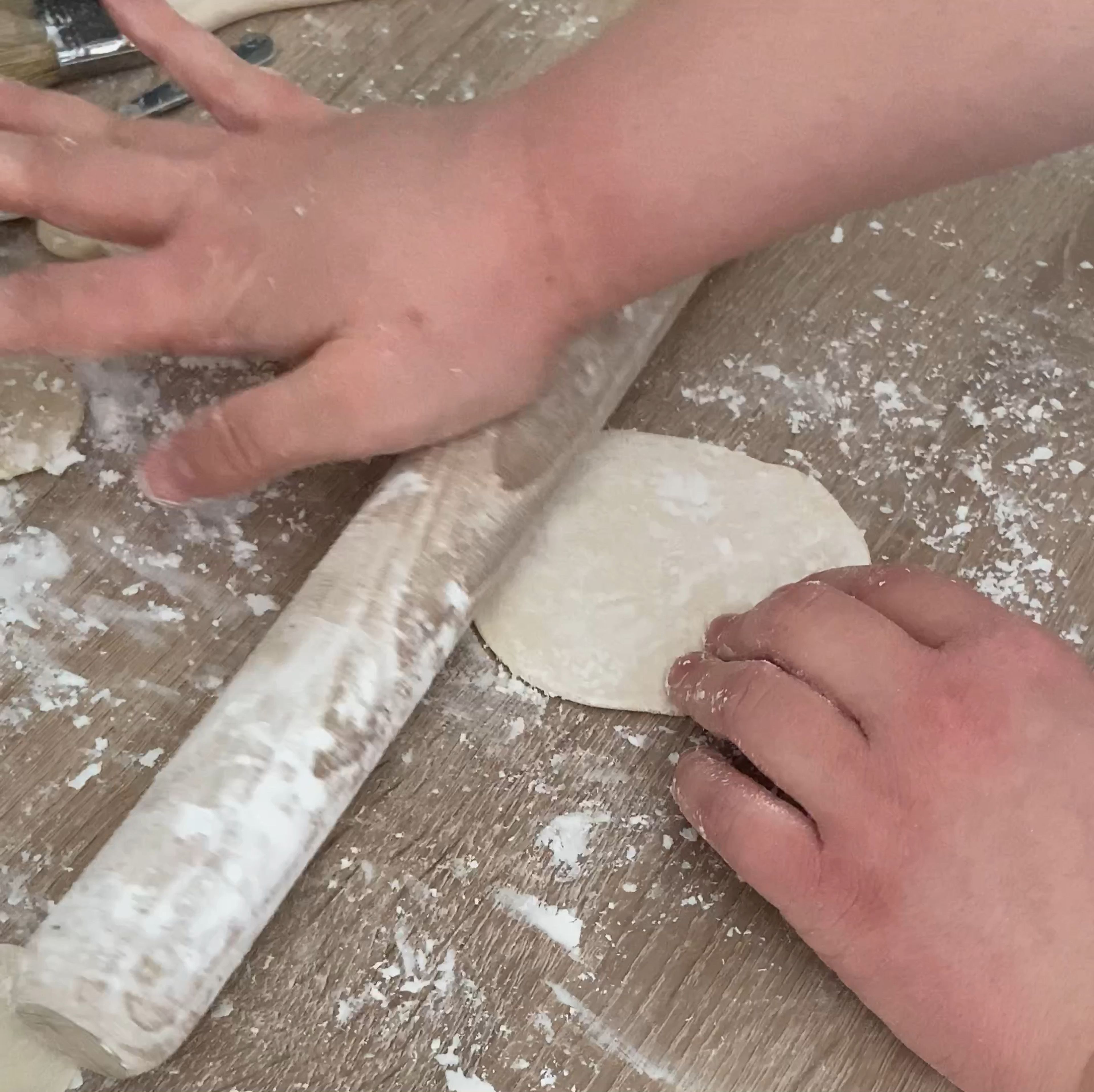 Die einzelne Kugel wird mit der Hand und einer guten Portion Stärke geplättet. Anschließend in kreisenden Bewegungen mit einem Nudelholz ausgerollt. Man kann hier auch mit reichlich Stärke zwei Kugeln gleichzeitig ausrollen.