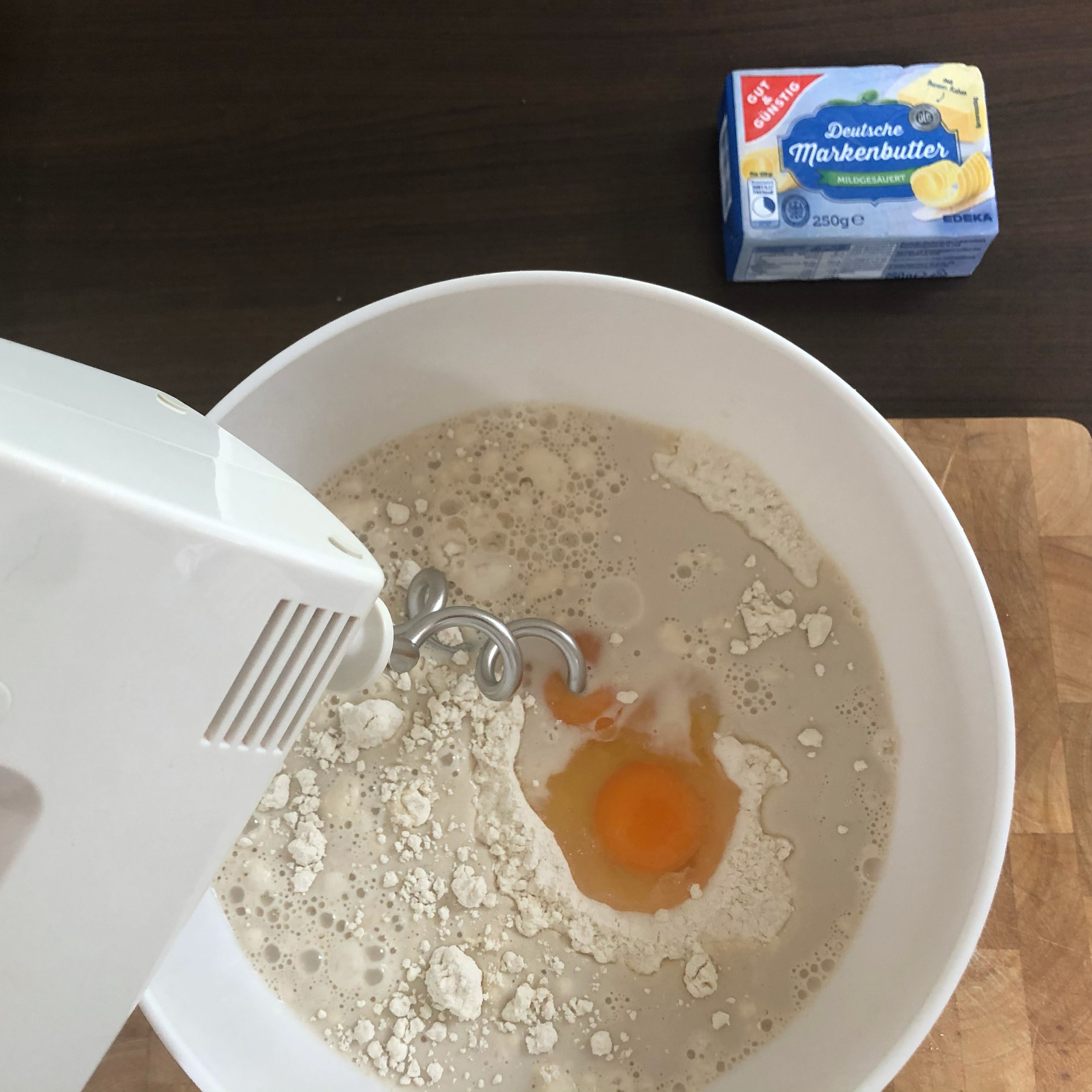 Das Ei, Eigelb und die Milch/Wasser/Hefe-Mischung in die Schüssel geben. Mit einem Handrührgerät und dem passenden Knethaken Aufsatz zu einem festen Teig kneten.
