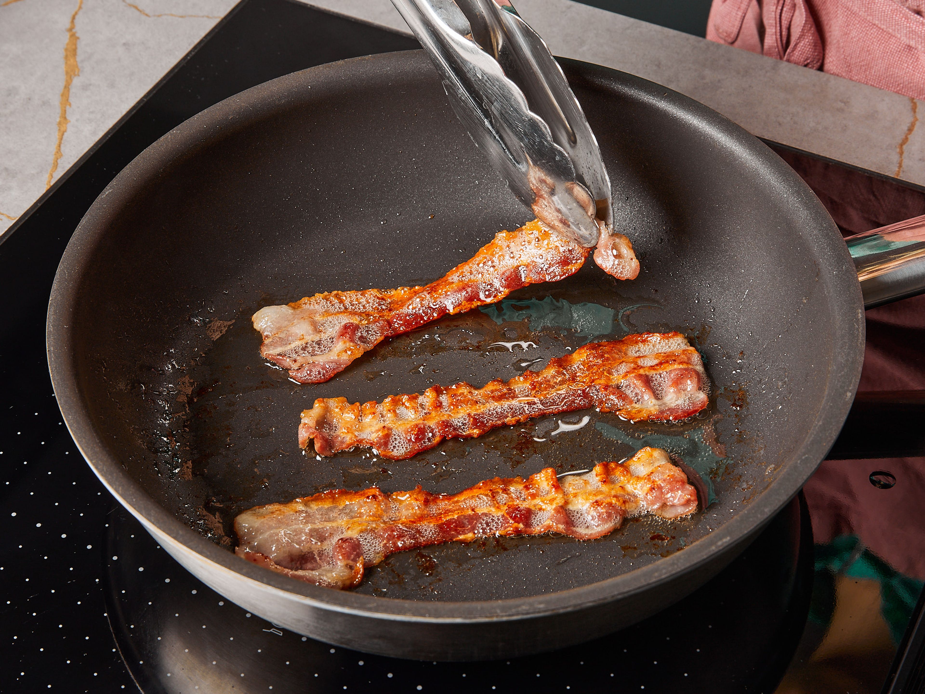 In einer beschichteten Bratpfanne den Bacon braten, bis er knusprig ist. Dann herausnehmen und auf einem Papiertuch abtropfen lassen.