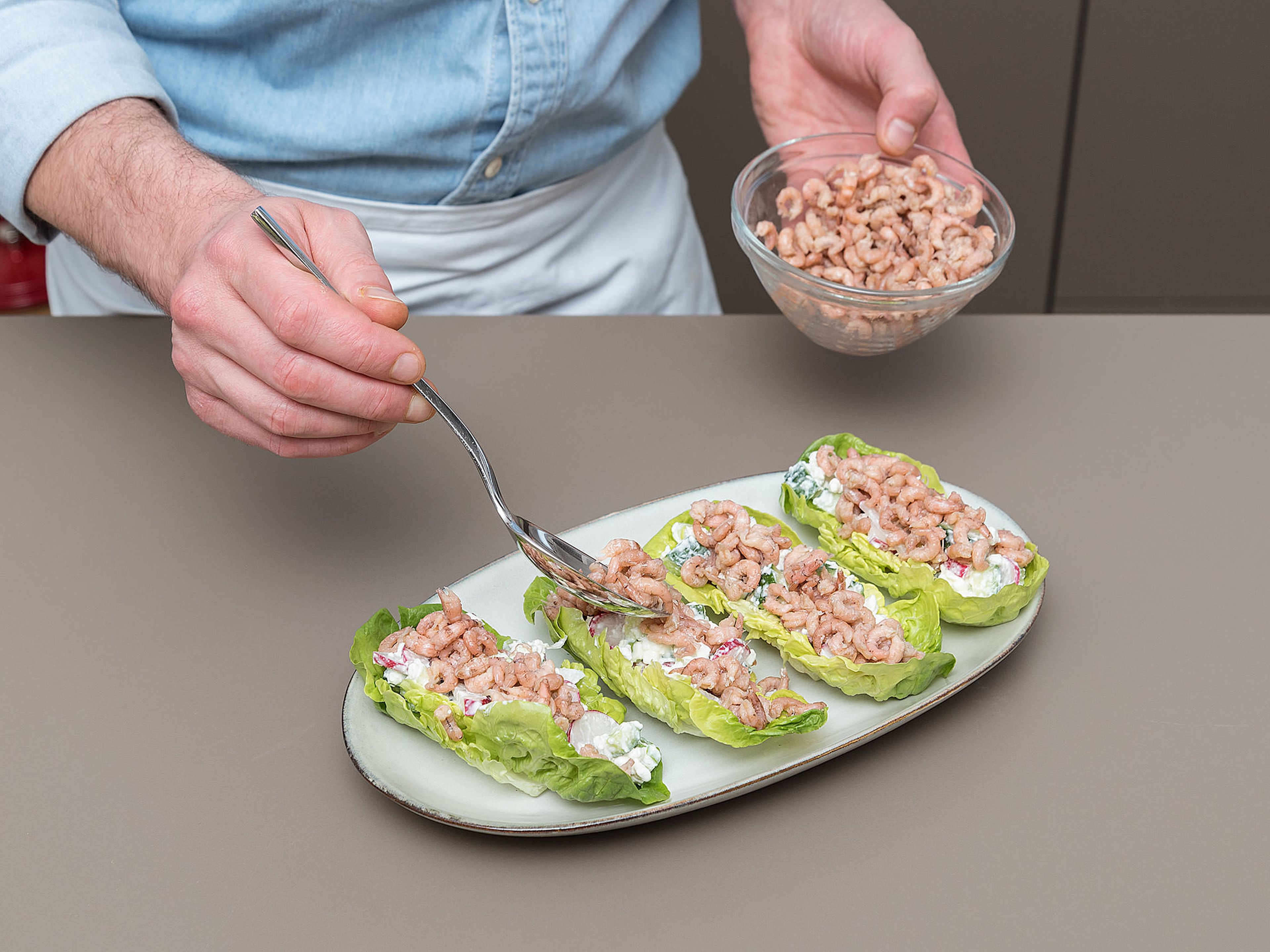 Die Salatblätter mit der Gurken-Hüttenkäse-Mischung vermengen und Nordseekrabben darauf verteilen.