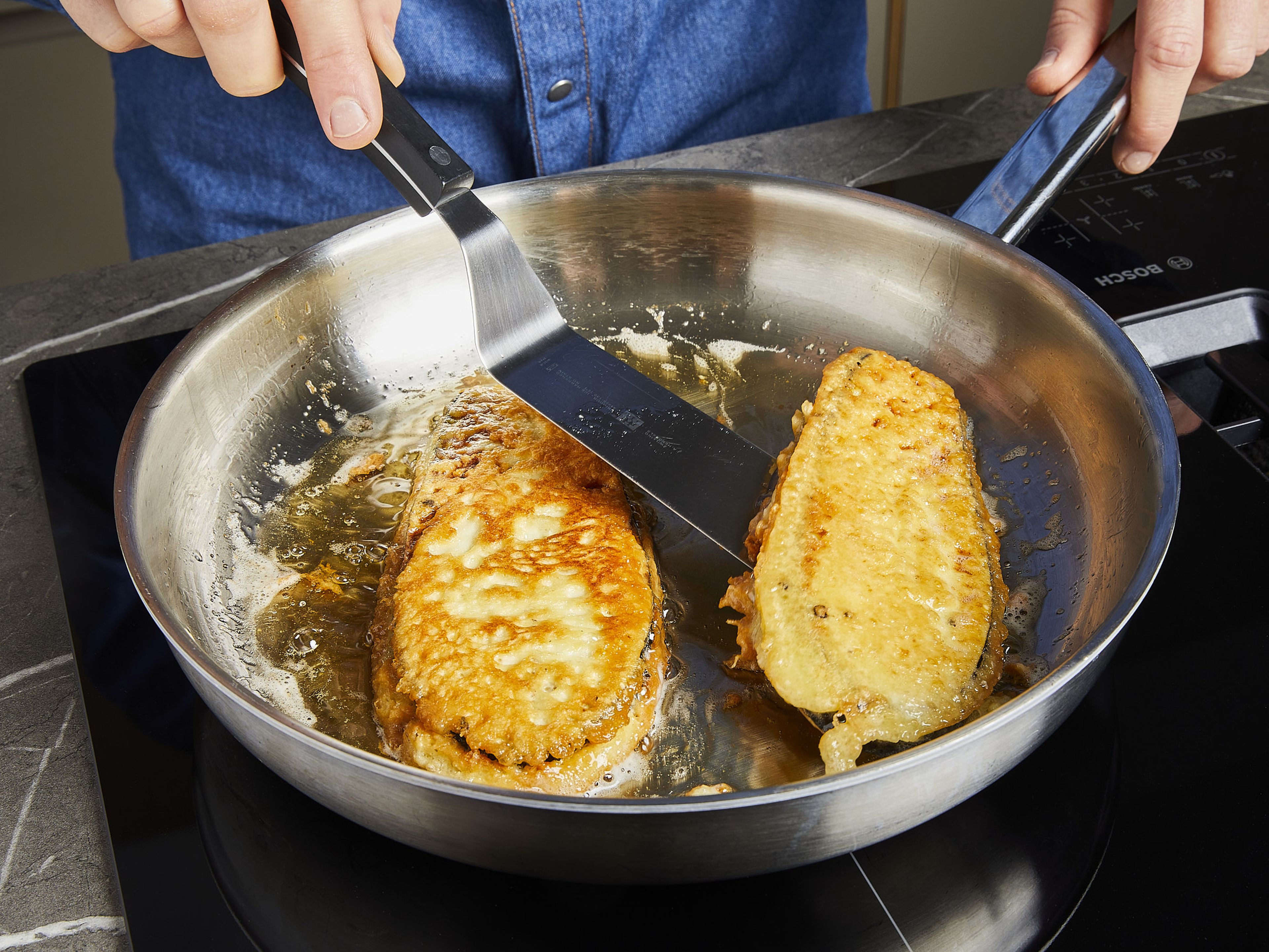 Rapsöl bei mittlerer Hitze in einer Pfanne erwärmen und Auberginenscheiben von beiden Seiten gold-gelb ausbraten. Anschließend auf Küchenpapier abtropfen lassen.