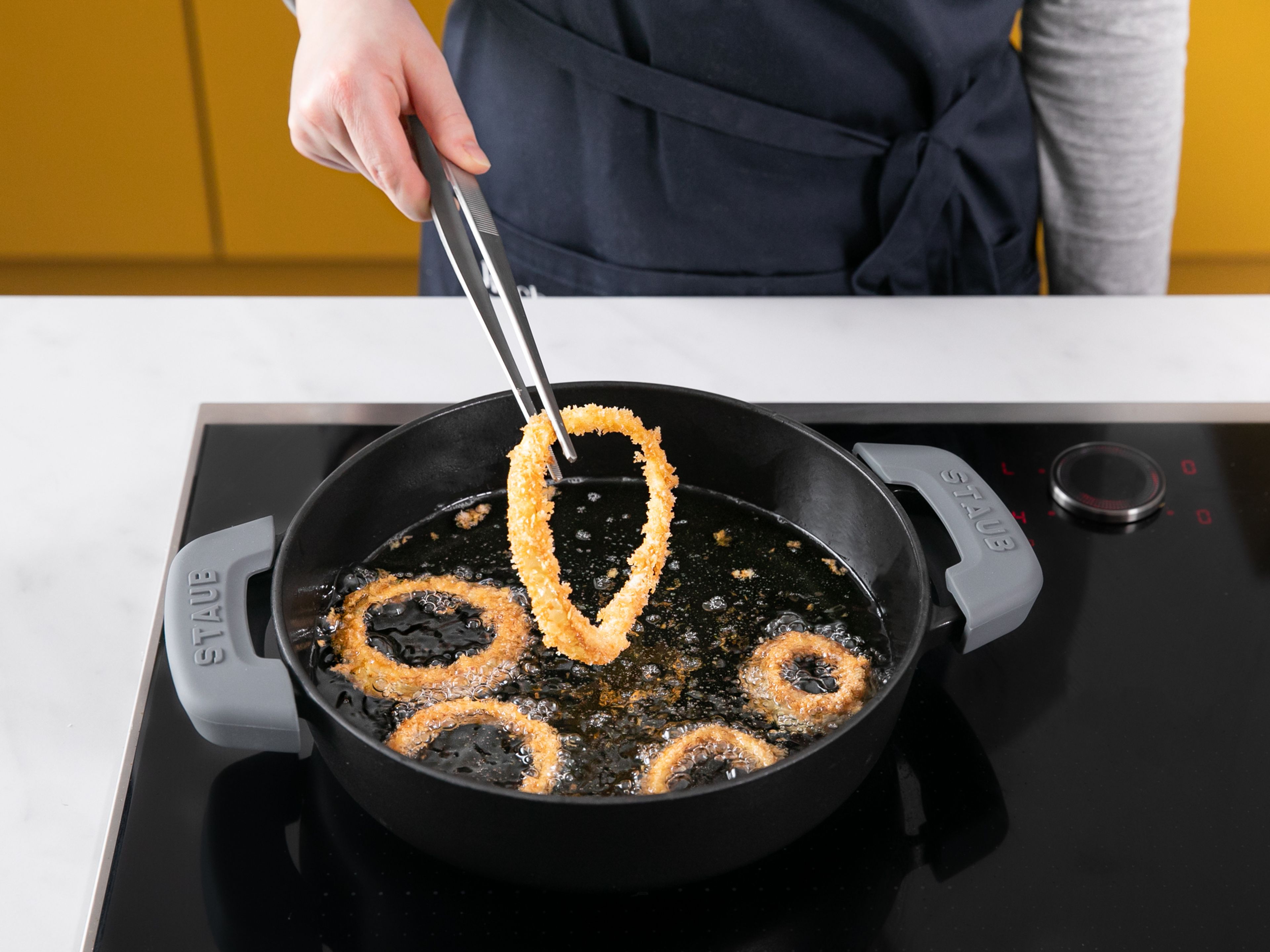 Add about 2.5-cm/1-in. of oil to a heavy-bottomed pot over medium-high heat. Let heat until the handle of a wooden spoon inserted into the pot forms bubbles all around it. Fry the onion rings in small batches until golden all over, approx. 5 min. Then transfer to a wire rack set inside a paper towel-lined baking sheet. Repeat with all onion rings.