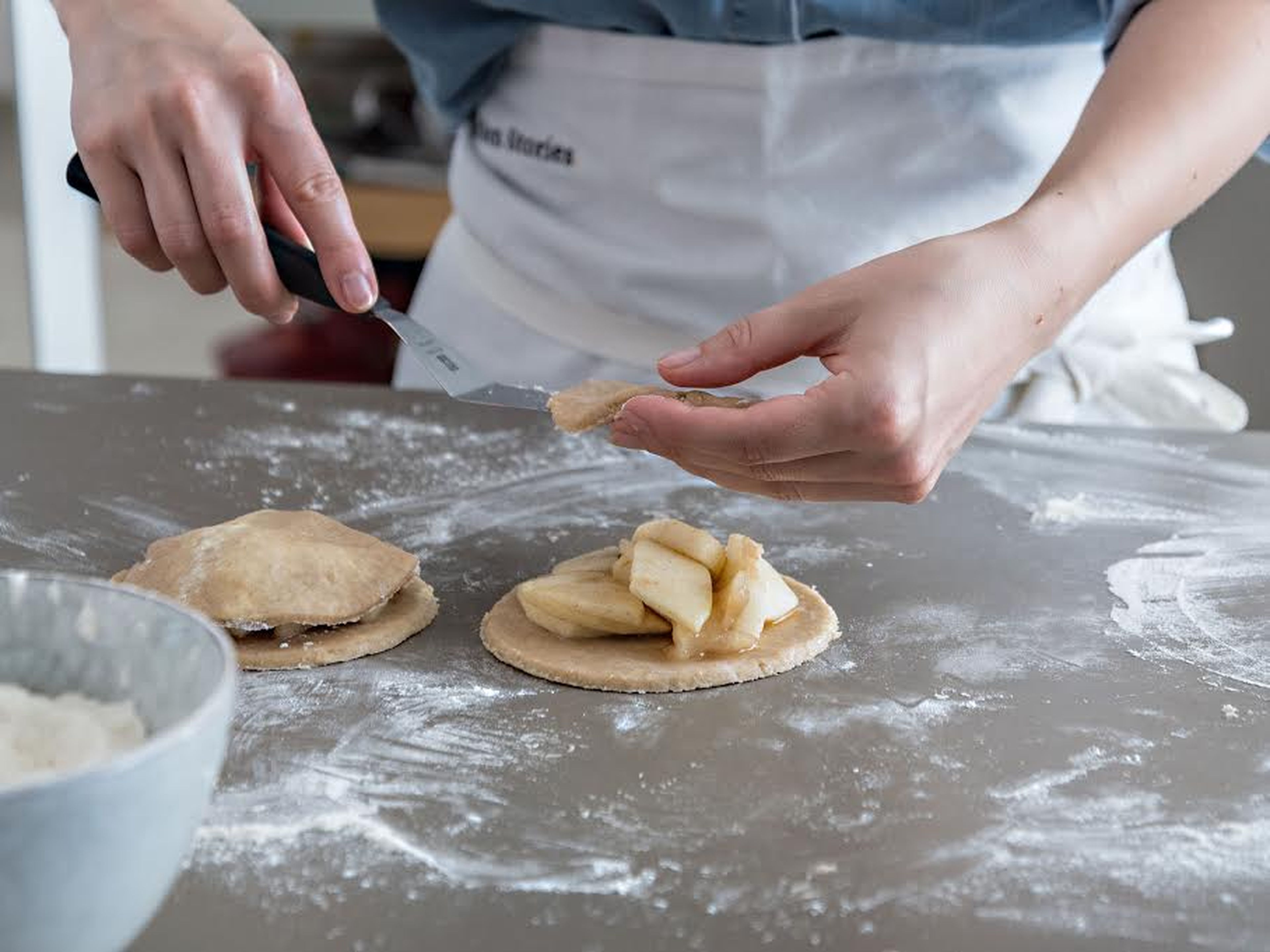 Preheat oven to 200°C/400°F and line a baking sheet with parchment paper. Lightly flour a work surface, unwrap dough, and dust with flour to prevent sticking. Roll out dough (approx. 0.5-cm/0.2-in. thick), and cut out circles using a cookie cutter or a knife. Divide apple filling between half of the dough circles, place the remaining circles on top, and press around the edges with a fork to seal. Transfer to prepared baking sheet.