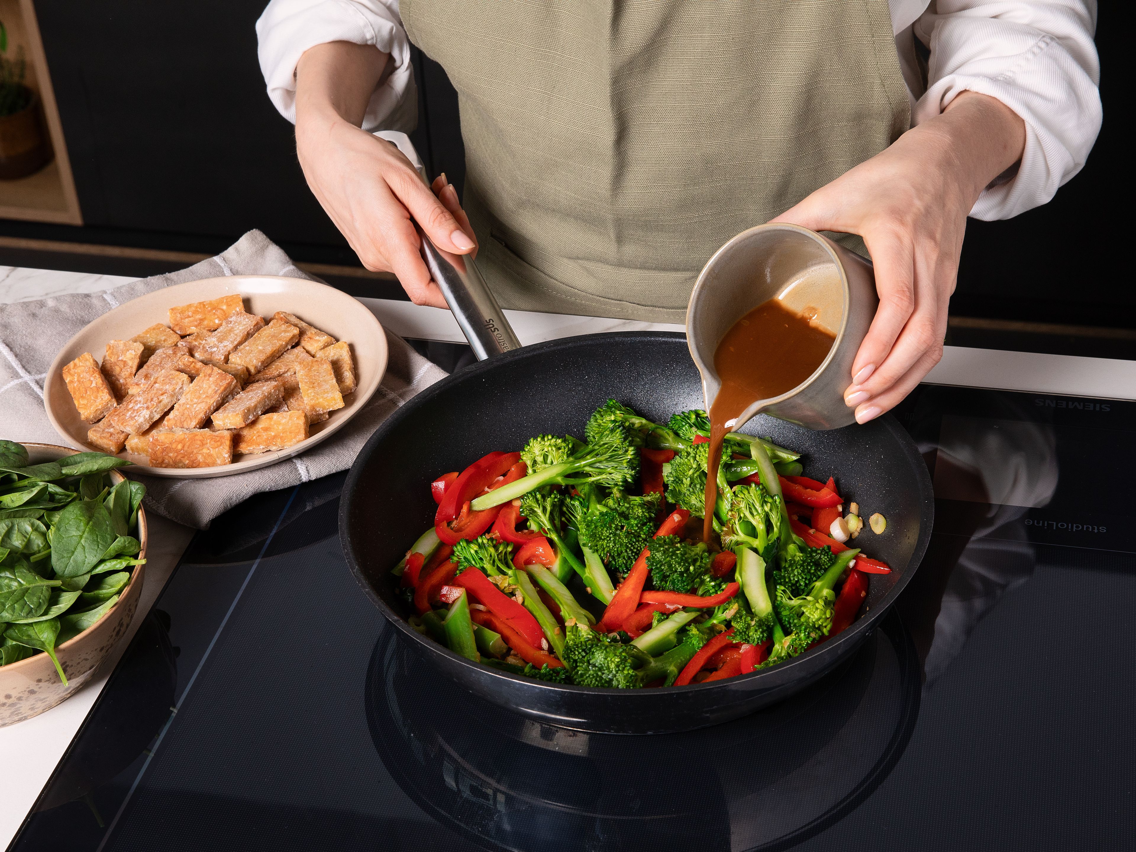 Sojasauce, Sweet-Chili-Sauce und die restliche Speisestärke mit Wasser verrühren und zum Gemüse geben. Kurz einkochen lassen, dann Tempeh und Spinat untermischen. Nach Belieben mit mehr Sojasauce abschmecken. Zum Schluss mit Sesamöl beträufeln und mit. Frühlingszwiebelgrün sowie Sesam bestreuen. Mit gekochtem Jasminreis servieren.