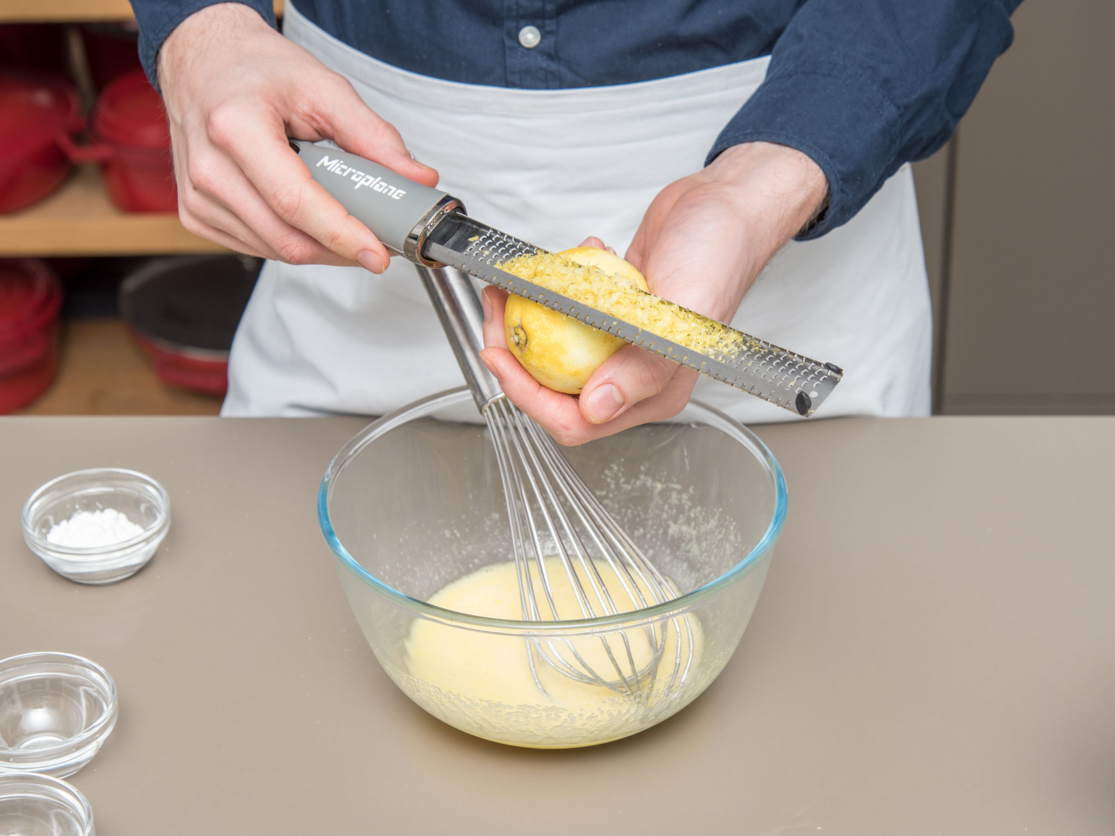 Ei, Eigelb und restlichen Zucker in einer Schüssel aufschlagen. Zitronensaft und -abrieb, sowie Stärke dazugeben und vermengen.