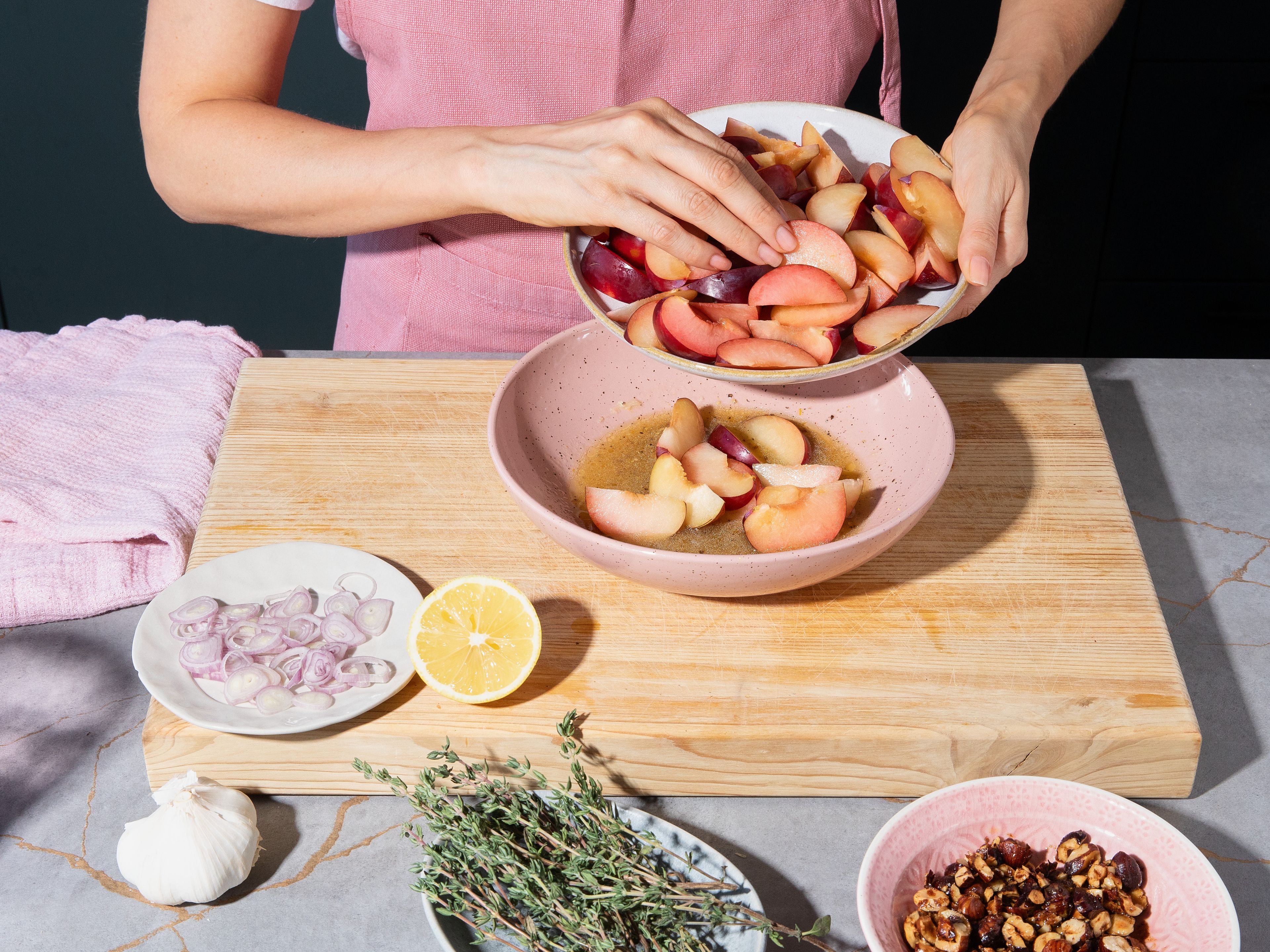 Stone plums and cut into wedges. Slice shallot into fine rings. Pluck thyme leaves. For dressing, finely grate garlic and mix with lemon juice, red wine vinegar, grainy Dijon mustard, remaining honey, and olive oil. Season with salt and pepper to taste. Mix plums with dressing and let sit for approx 5 min.